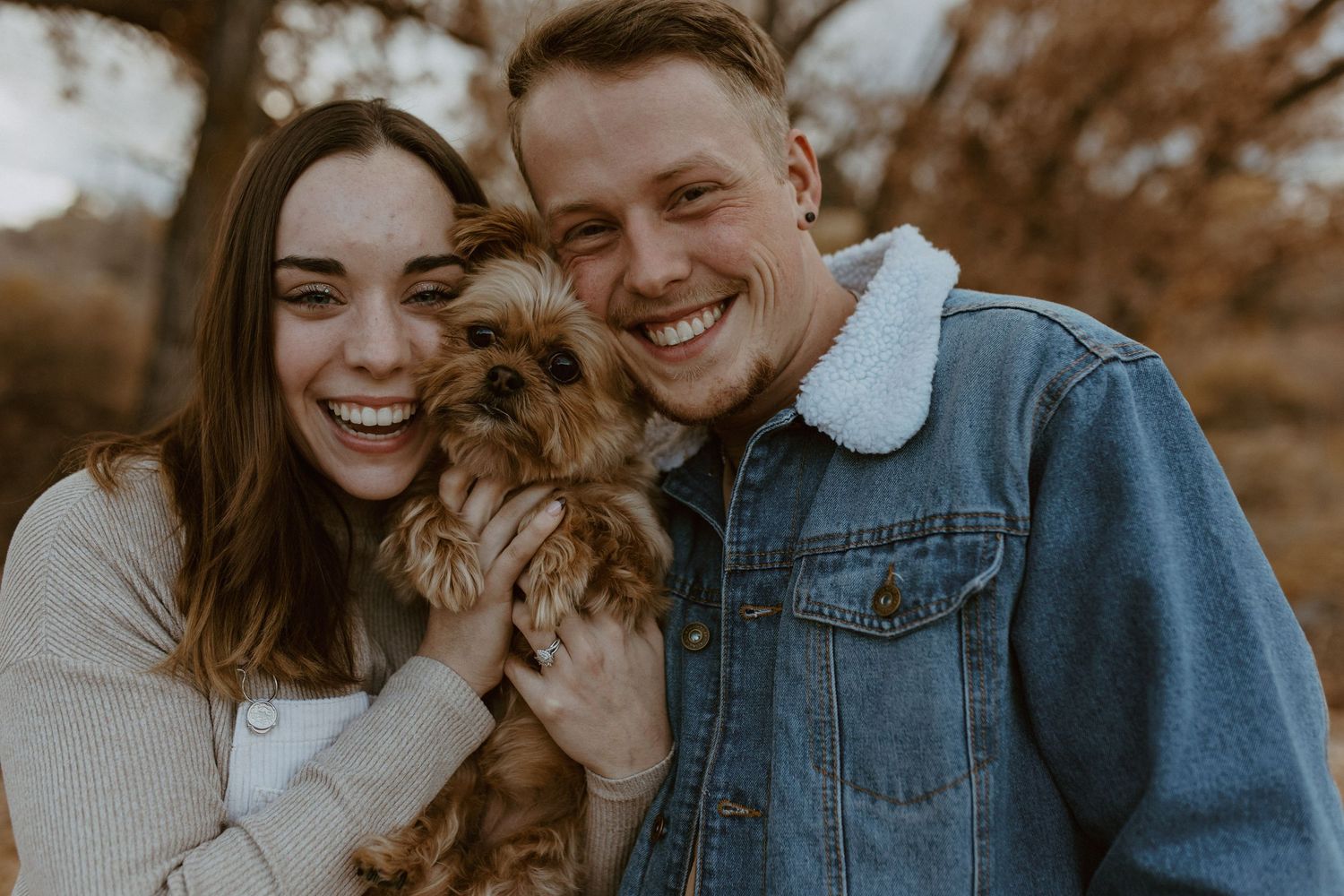 couple smiling at camera with dog in grand junction fall photoshoot colorado