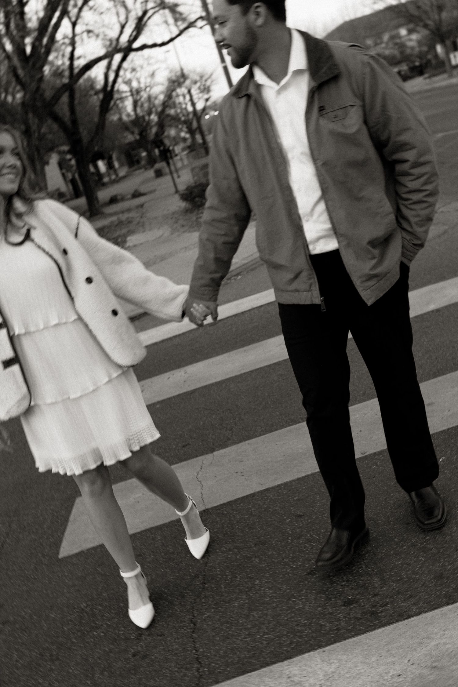 black and white street style engagement photography of couple walking down the street and holding hands  in downtown grand junction