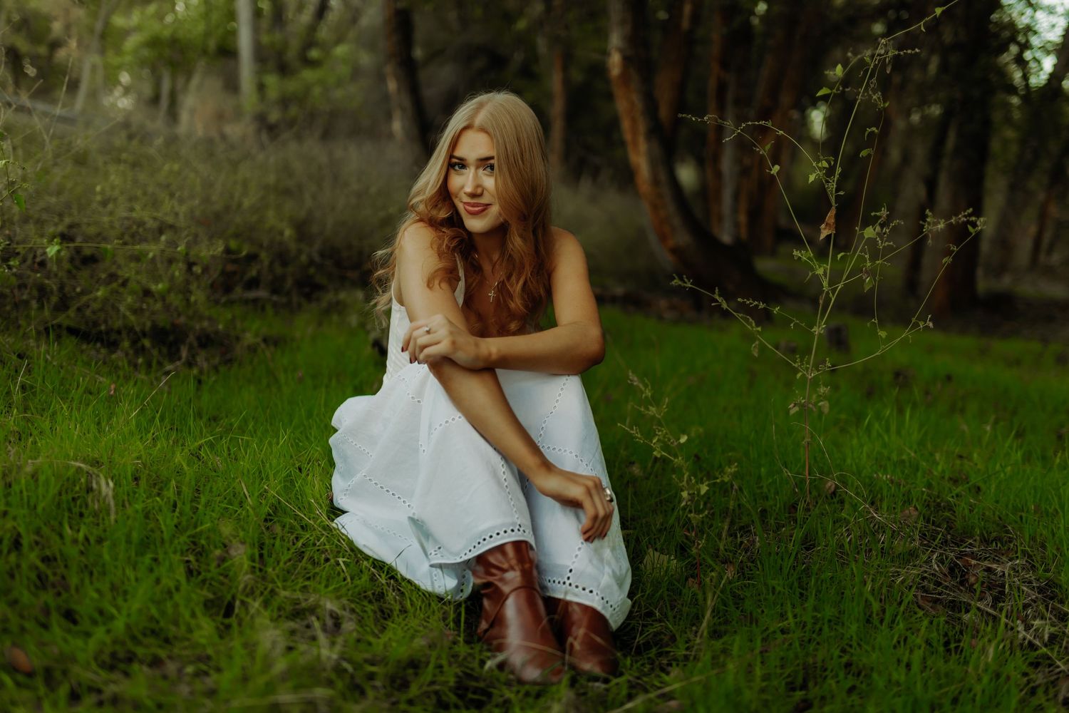 girl sitting in grass in a bright field during grand junction colorado photoshoot, senior photography