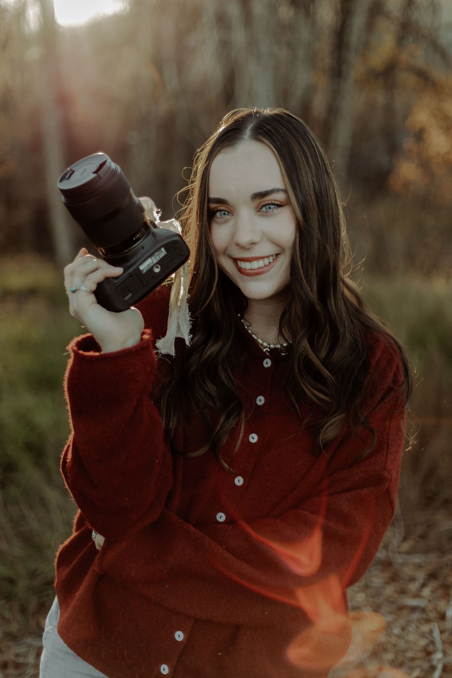 colorado photographer smiling at camera while holding her camera in hand
