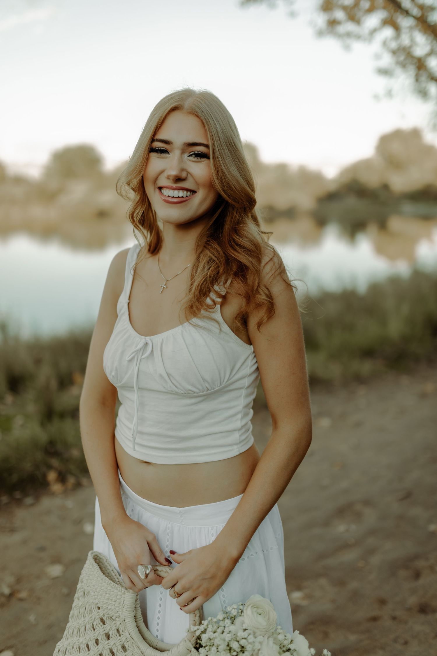 girl smiling at photo by scenic river and field with flowers during grand junction colorado senior photography session