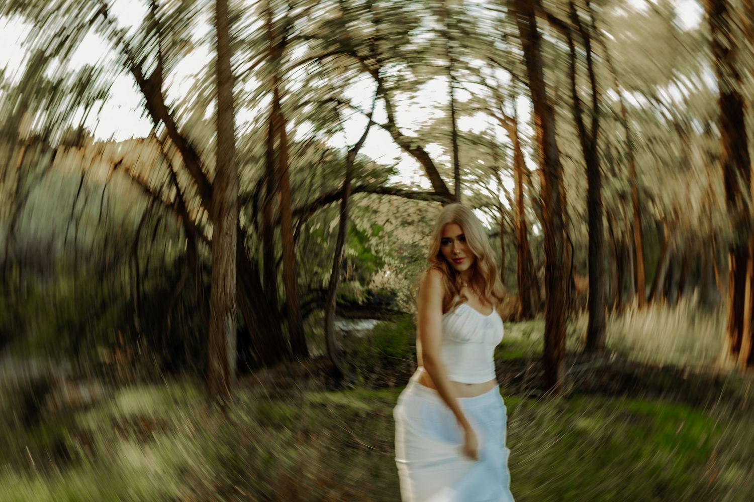 blurry forest photo of girl standing in trees during senior photoshoot in grand junction colorado