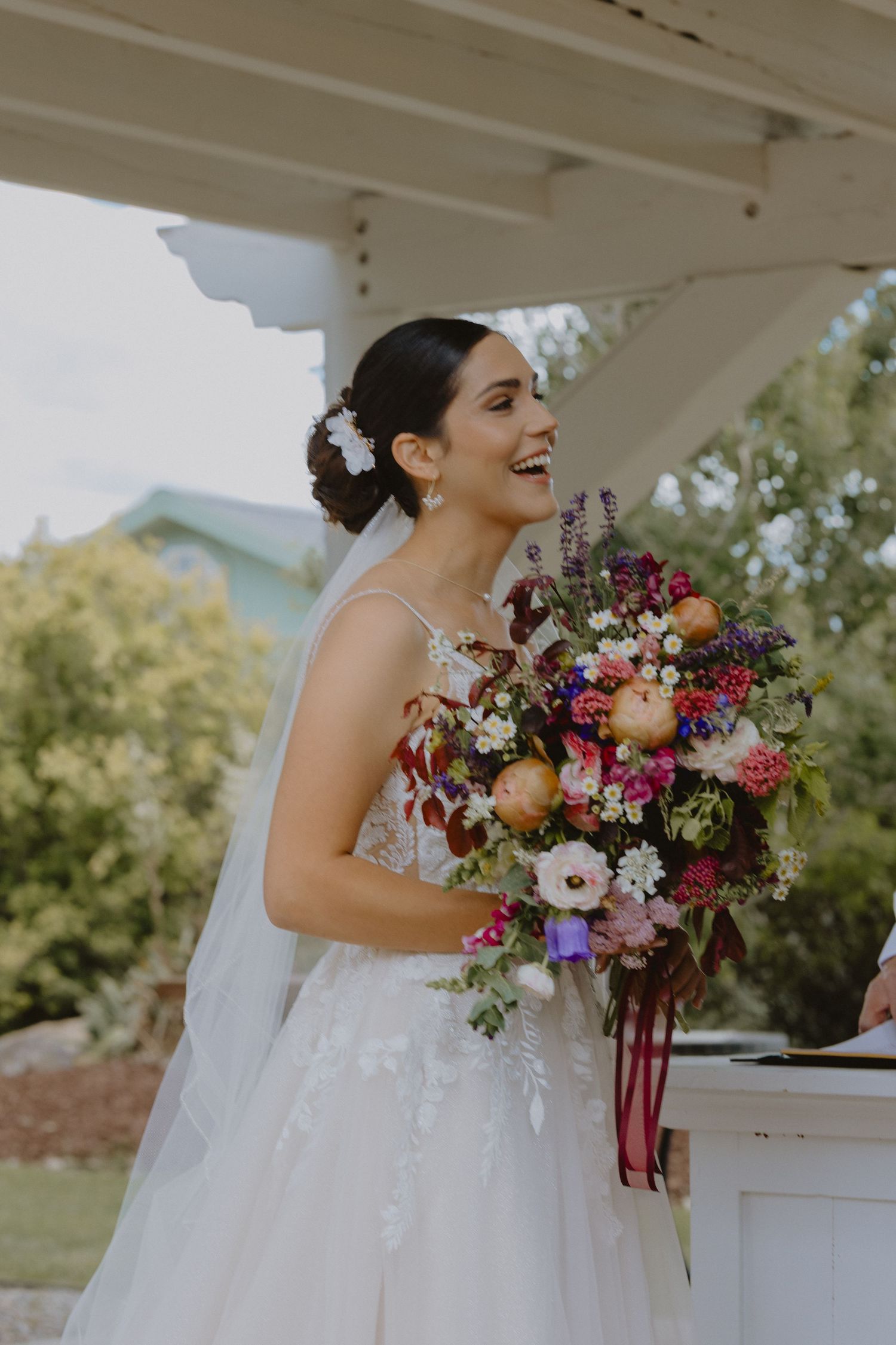 bride smiling with large bouquet during ceremony in wedding