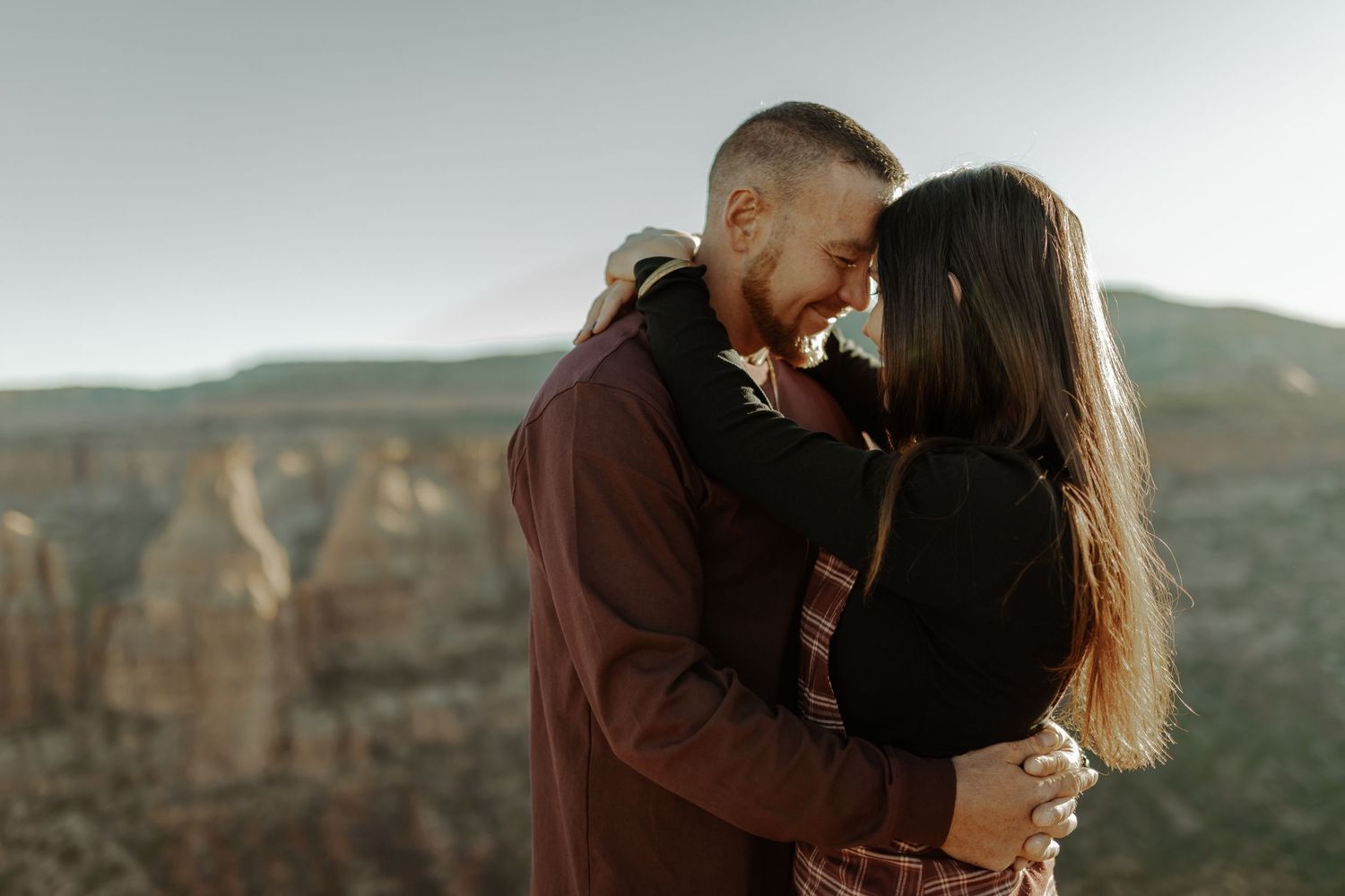colorado national monument photography engagement photoshoot, couple posing on mountain and leaning their heads together