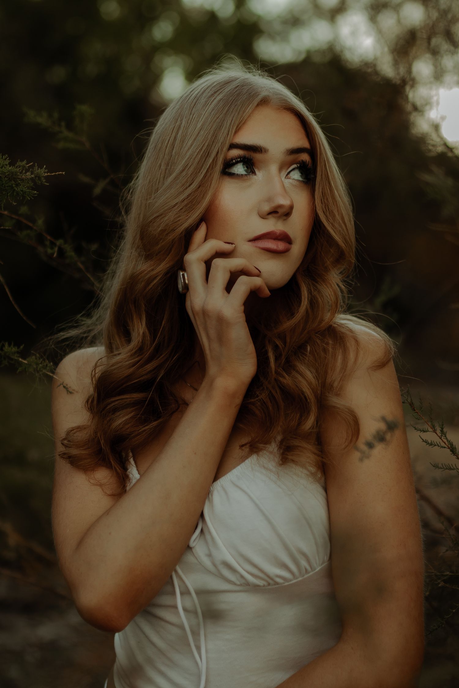 senior photoshoot of stunning girl posing in the trees with her hand on her face, editorial photoshoot in grand junction colorado