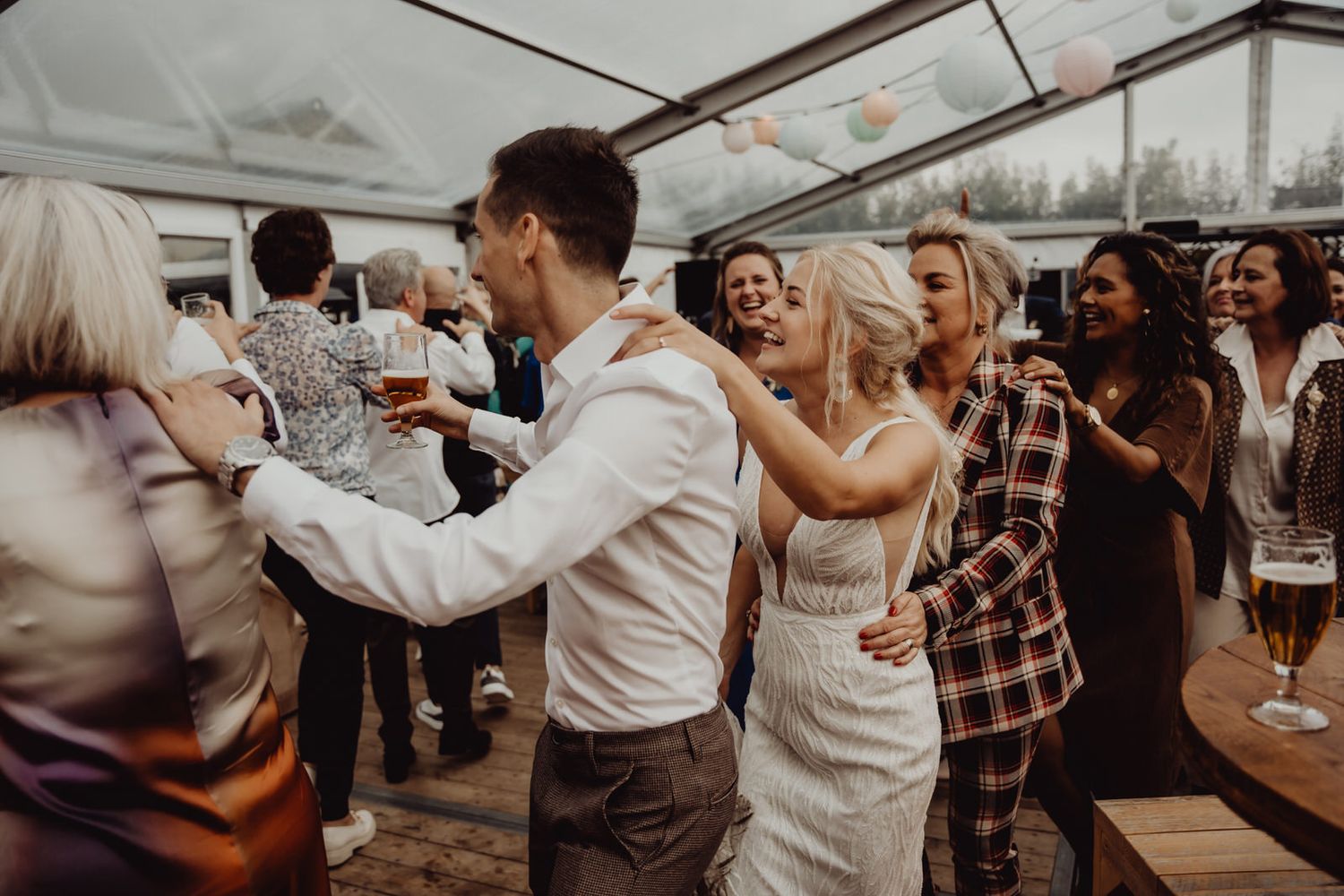Wedding reception guests dancing and celebrating in a bright venue.