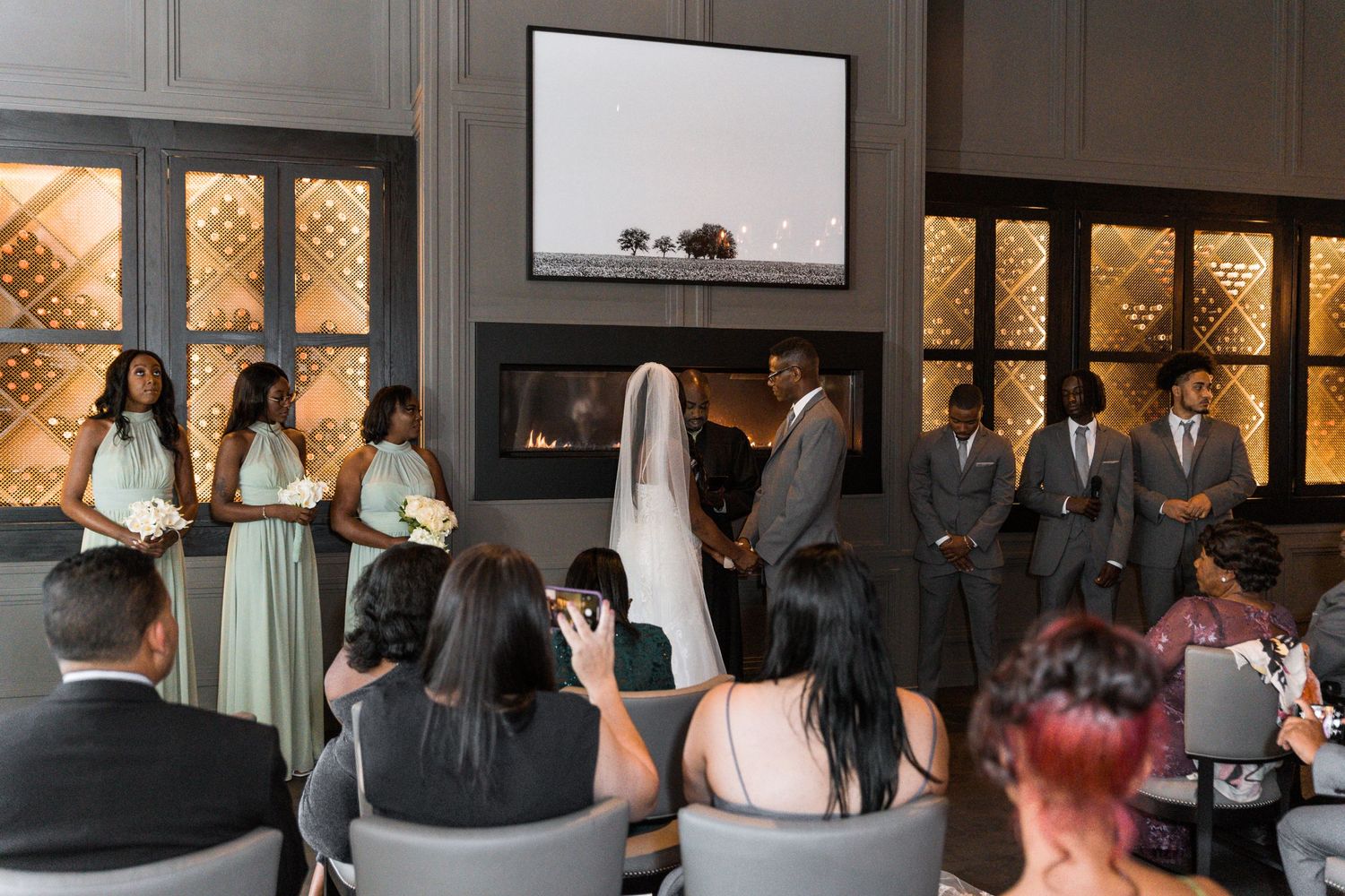 wedding couple saying vows at alter with fireplace with backlit wine room