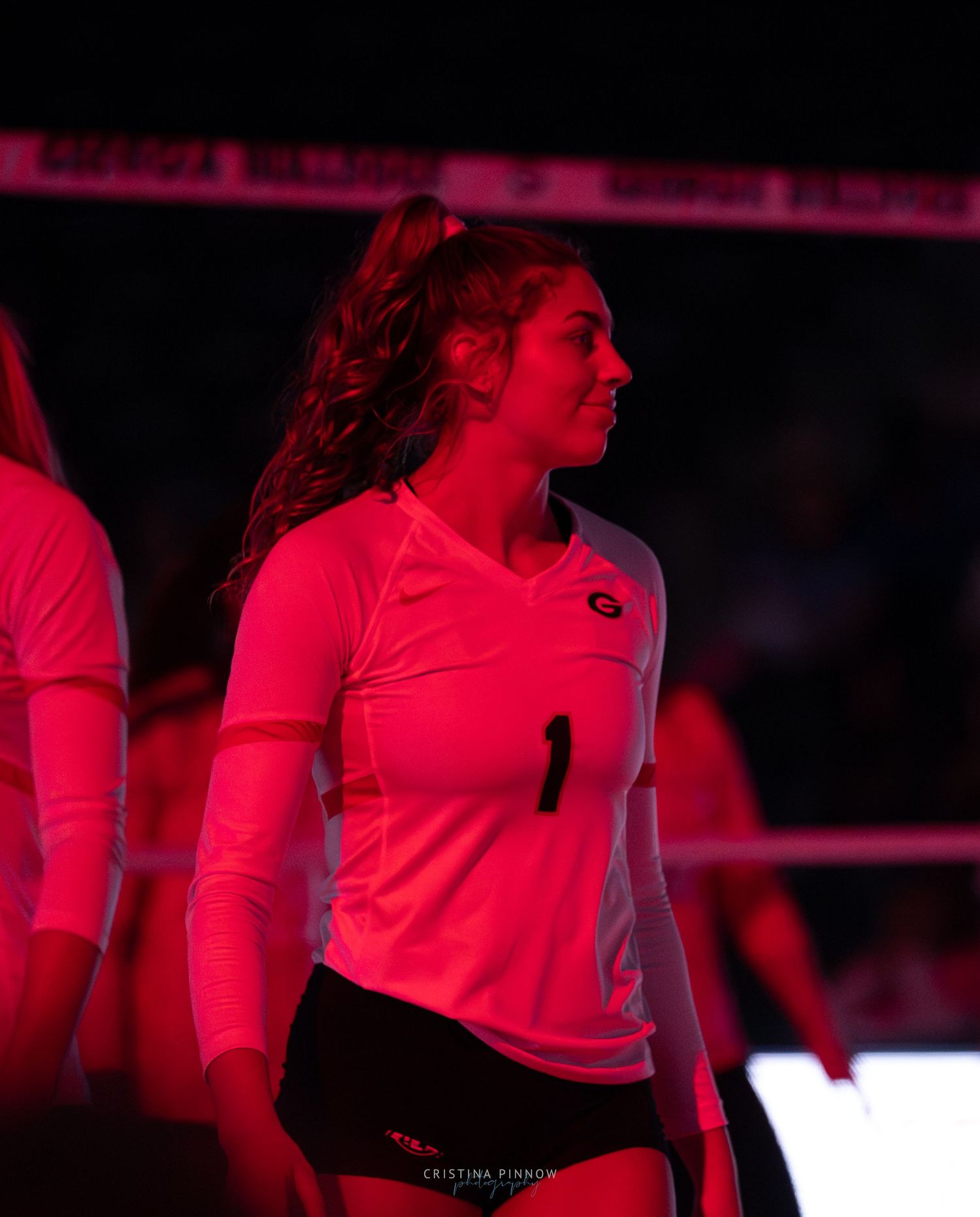 Athletes in red jerseys stand under dramatic lighting during a pre-game ceremony.