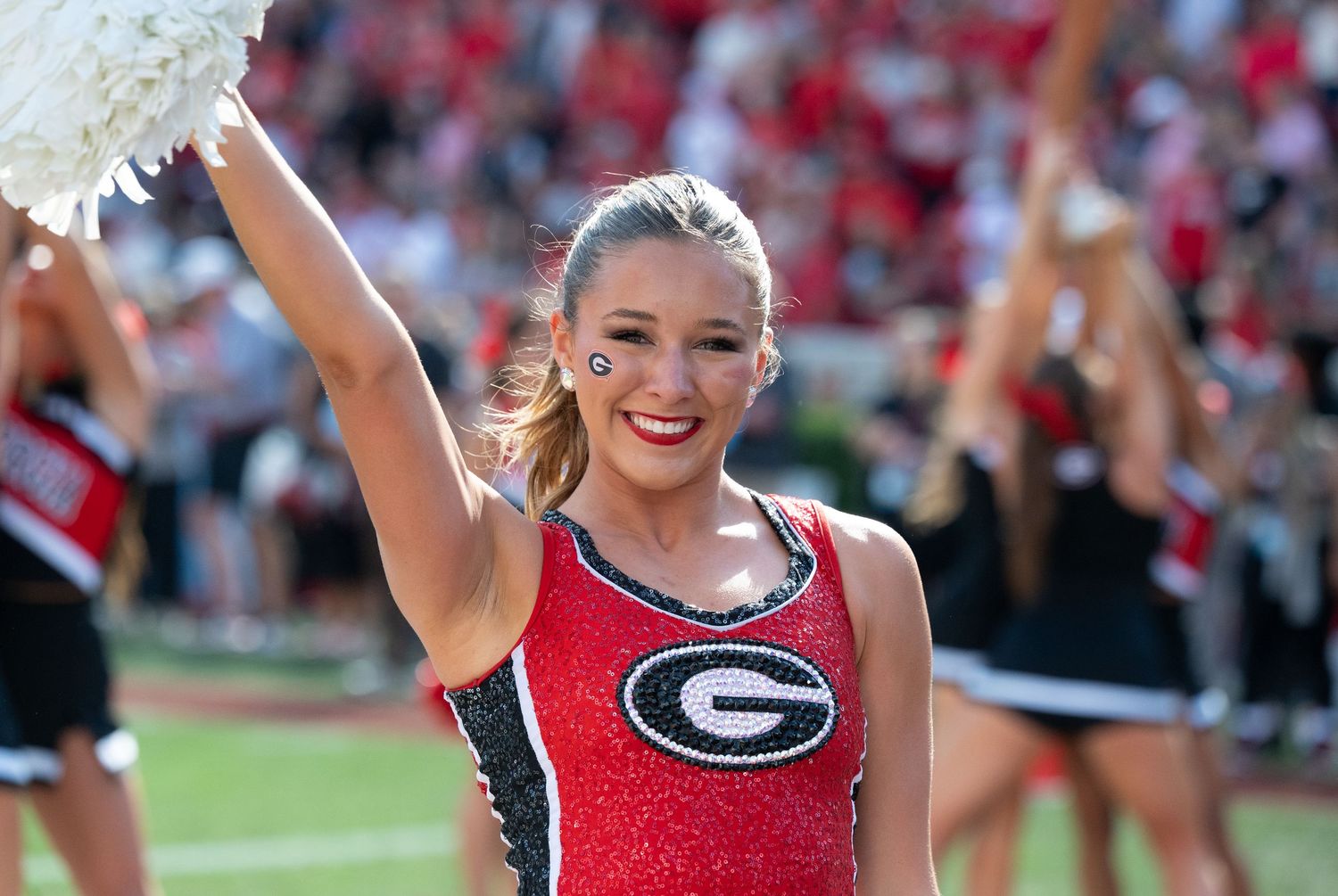 Cheerleaders in red uniforms performing at a stadium event.