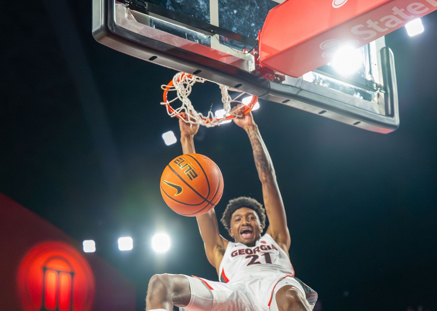 Basketball players leap high to score during intense indoor game action.