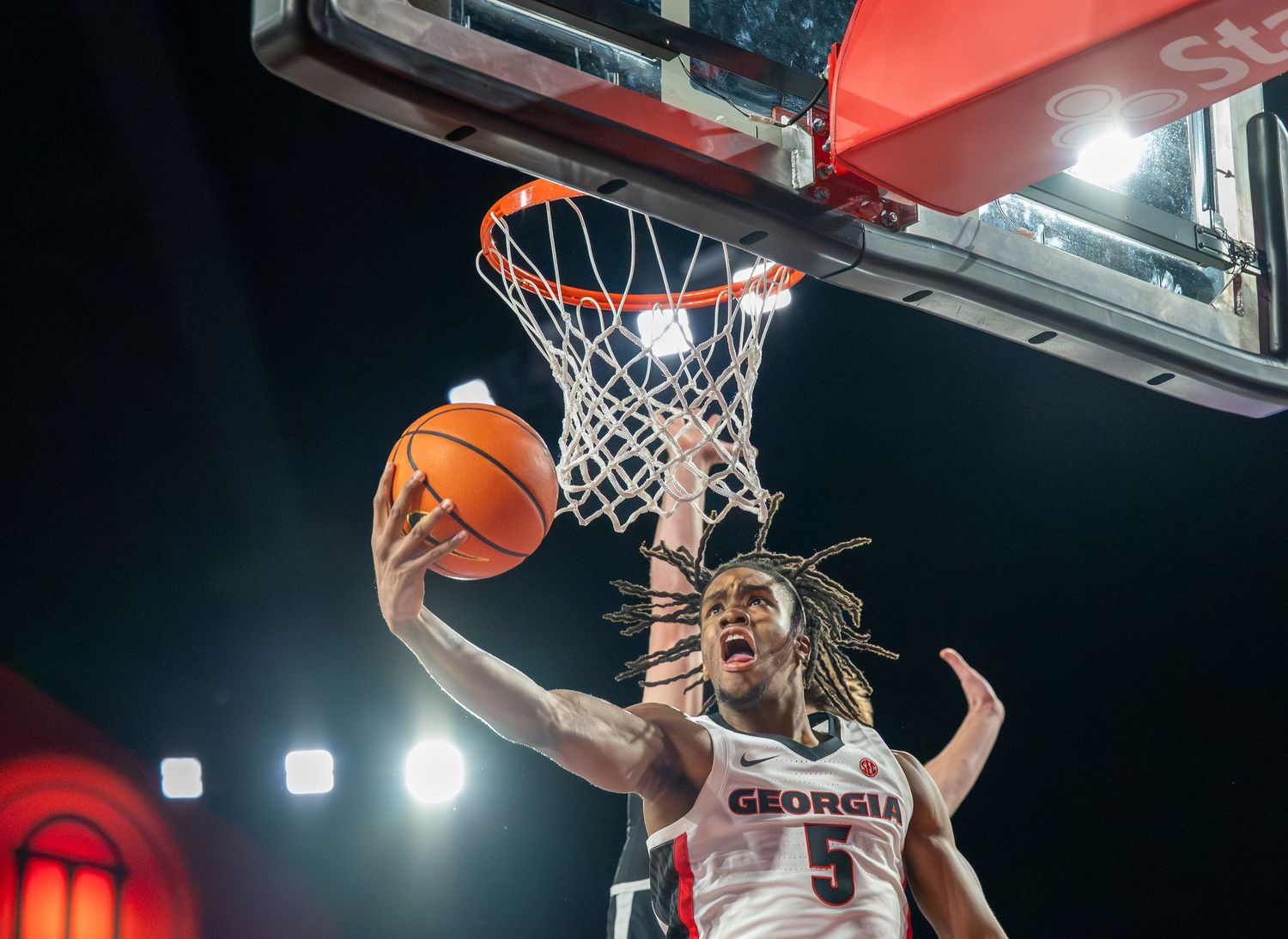 Basketball players jumping for a rebound during an intense indoor game.