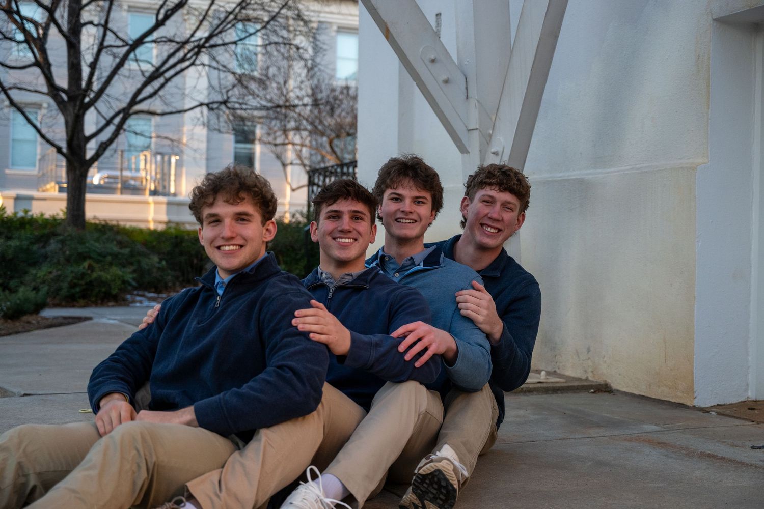 Students in casual attire sitting and laughing together under architectural columns.