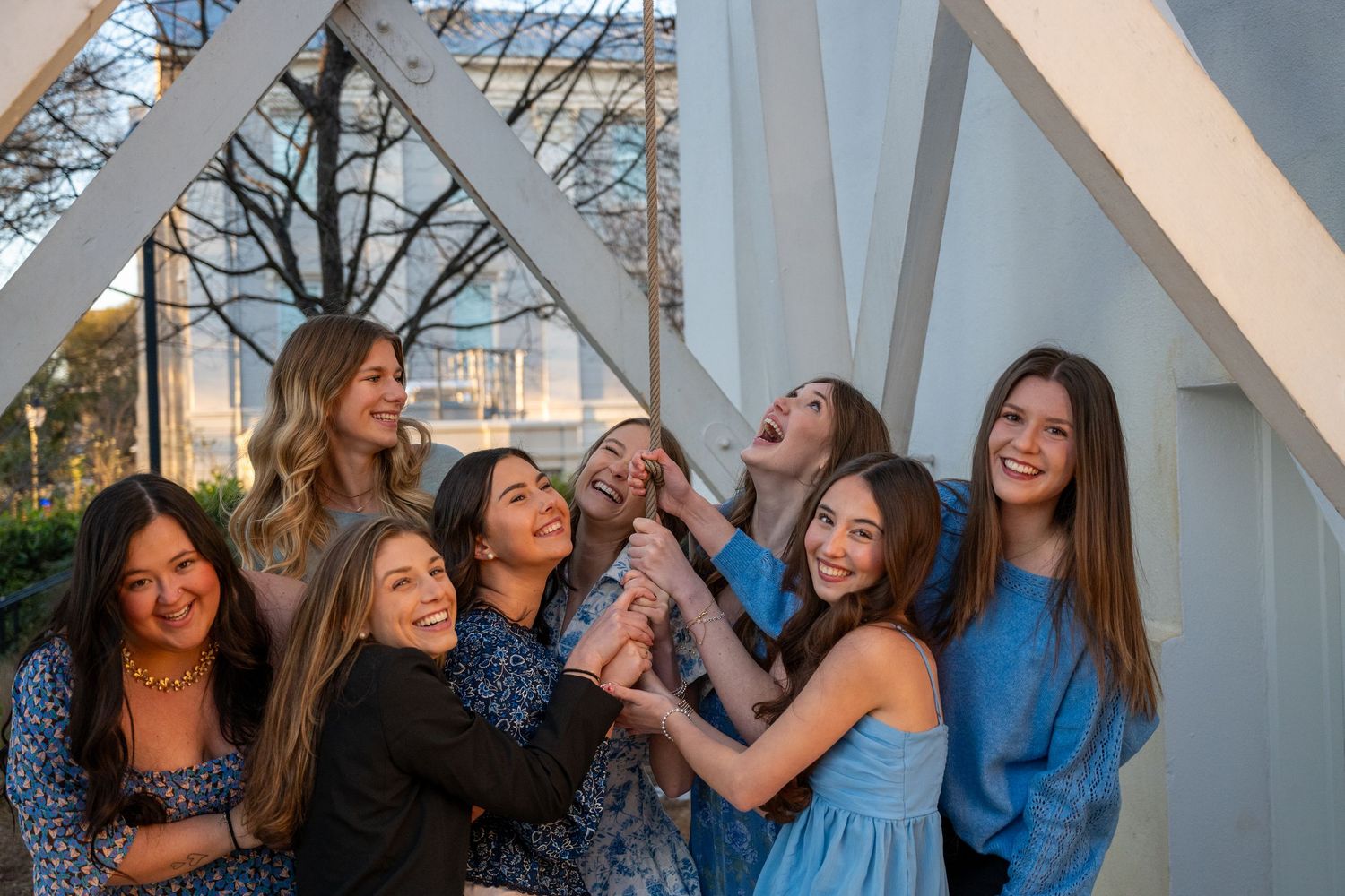 Group of friends laughing together under white architectural beams at sunset.
