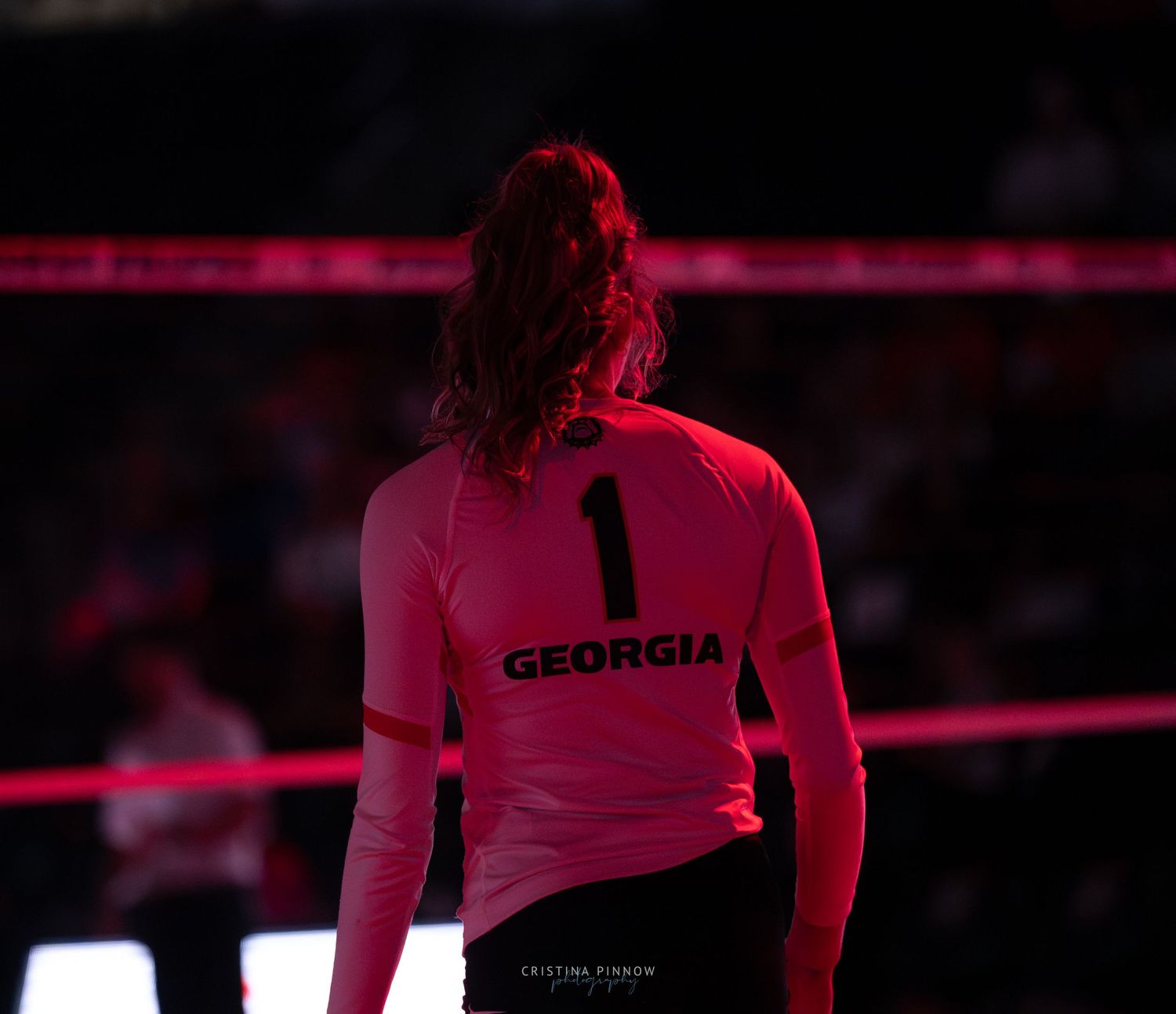 Athletes in red lighting performing on a dark stage during a competition or performance.