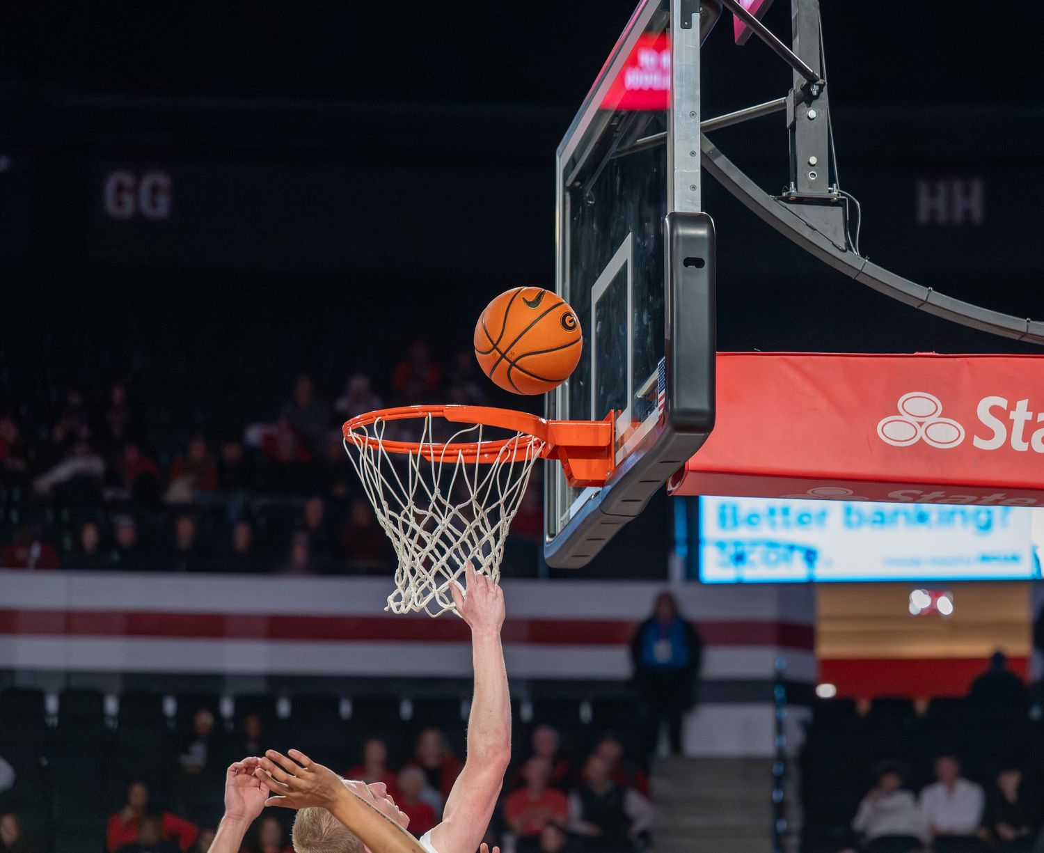 Basketball player attempts to score at the rim during an intense game moment.