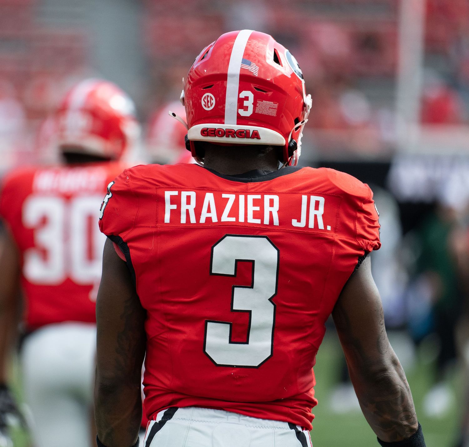Football player wearing red jersey number 3 on the field.