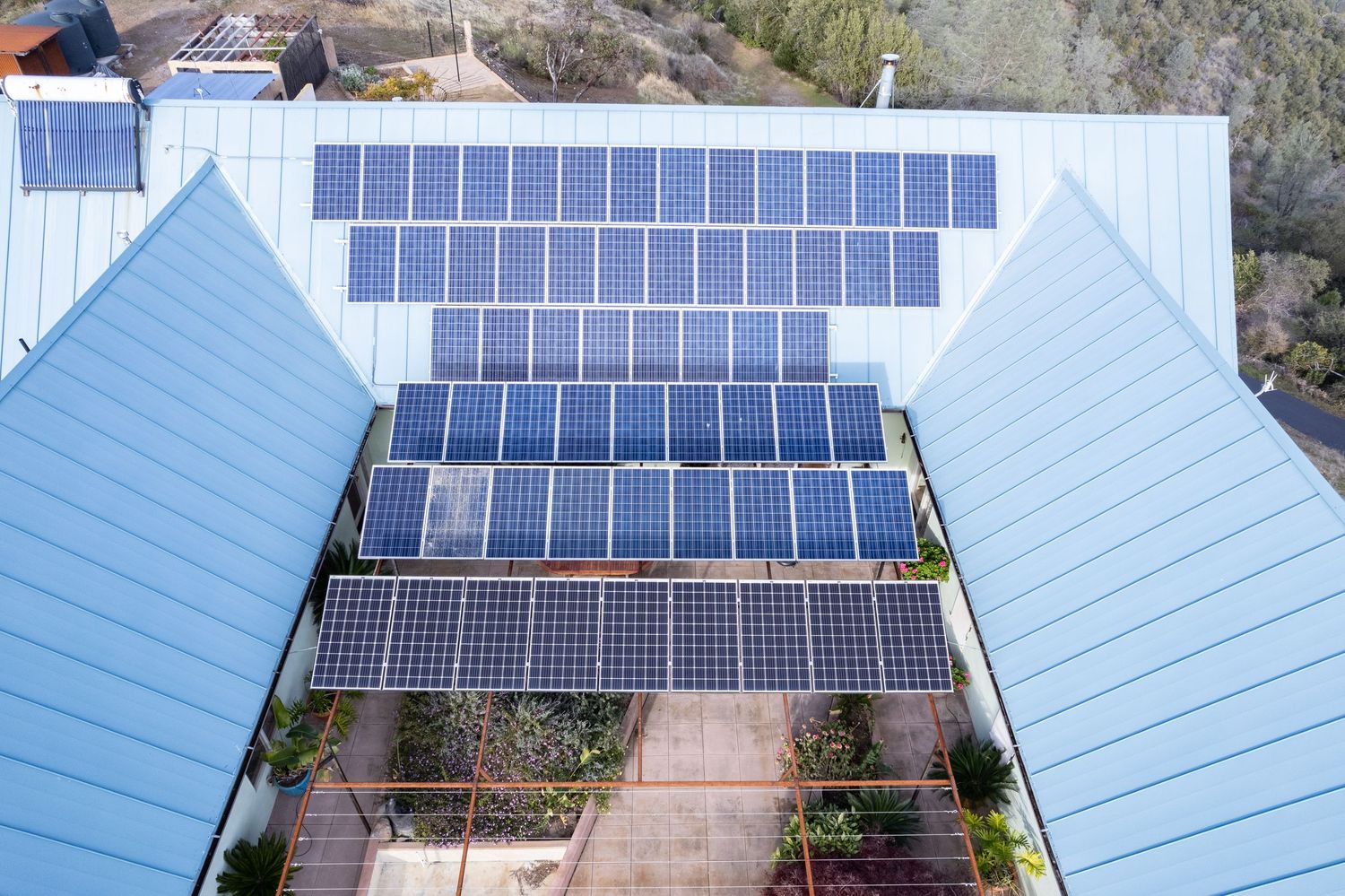 Elevated view of residential property showing dual solar panel arrays Forest Ranch CA. Elevated drone shot