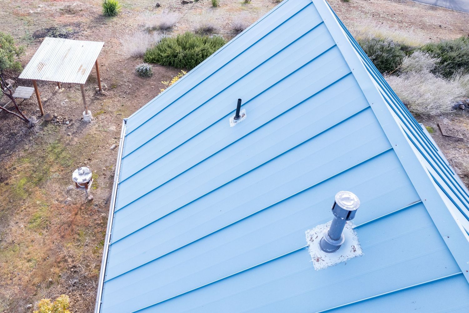 Elevated aerial showing metal roof solar panels and surrounding property, Forest Ranch. Elevated drone shot