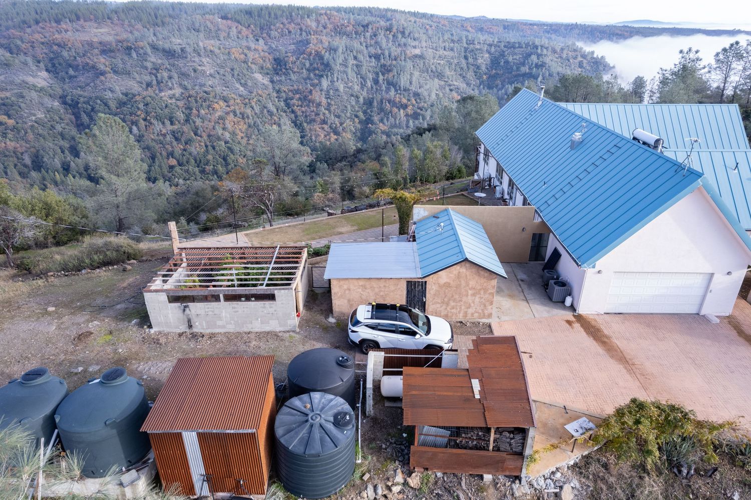 Aerial drone survey of Forest Ranch property showing roof and surrthe ounding hillside terrain. Elevated drone shot