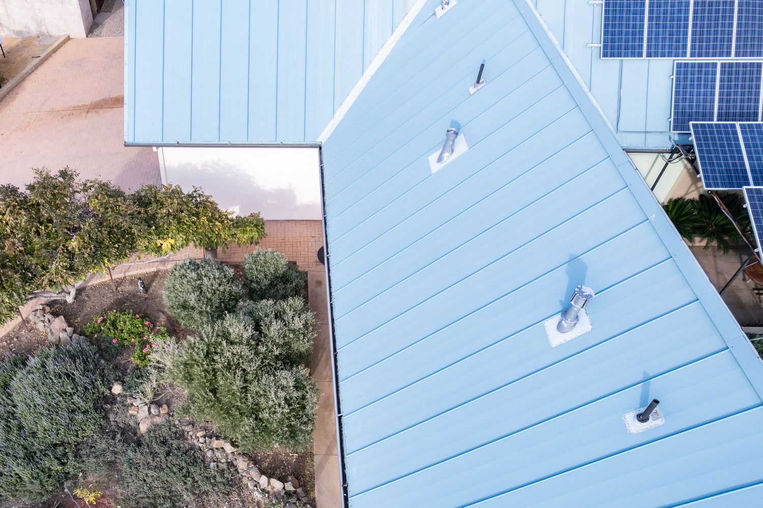 Overhead drone survey showing roof penetrations and metal panel condition. Elevated drone shot
