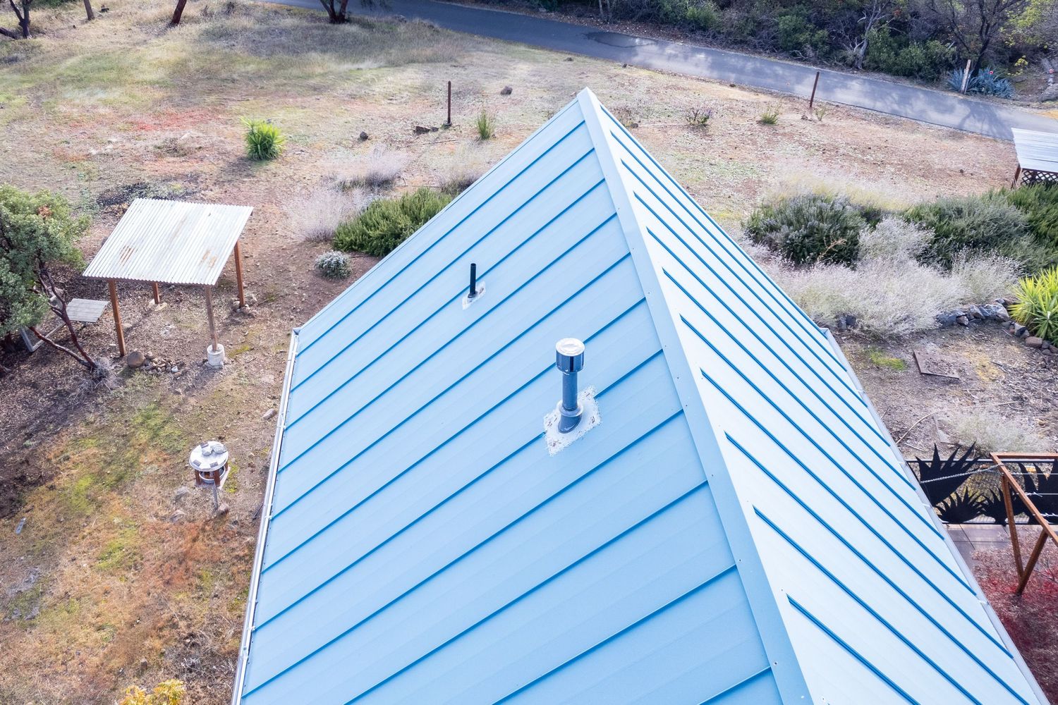 Overhead view of metal roof ridge cap and ventilation pipe Forest Ranch California