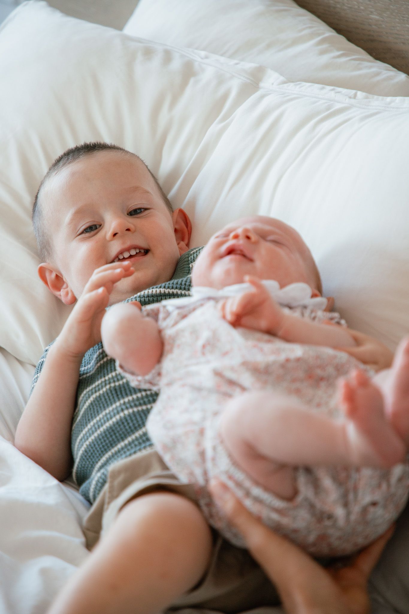 toddler holding newborn sister in their home