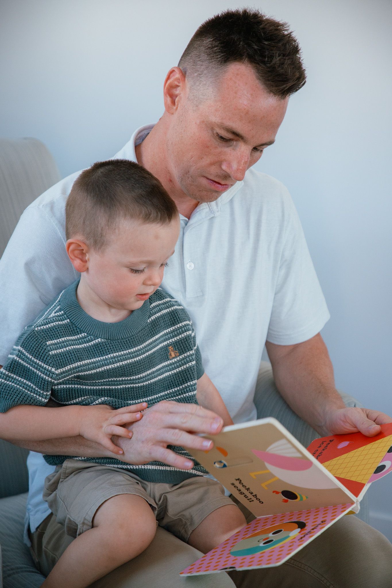 dad reading a children's book to son and smiling