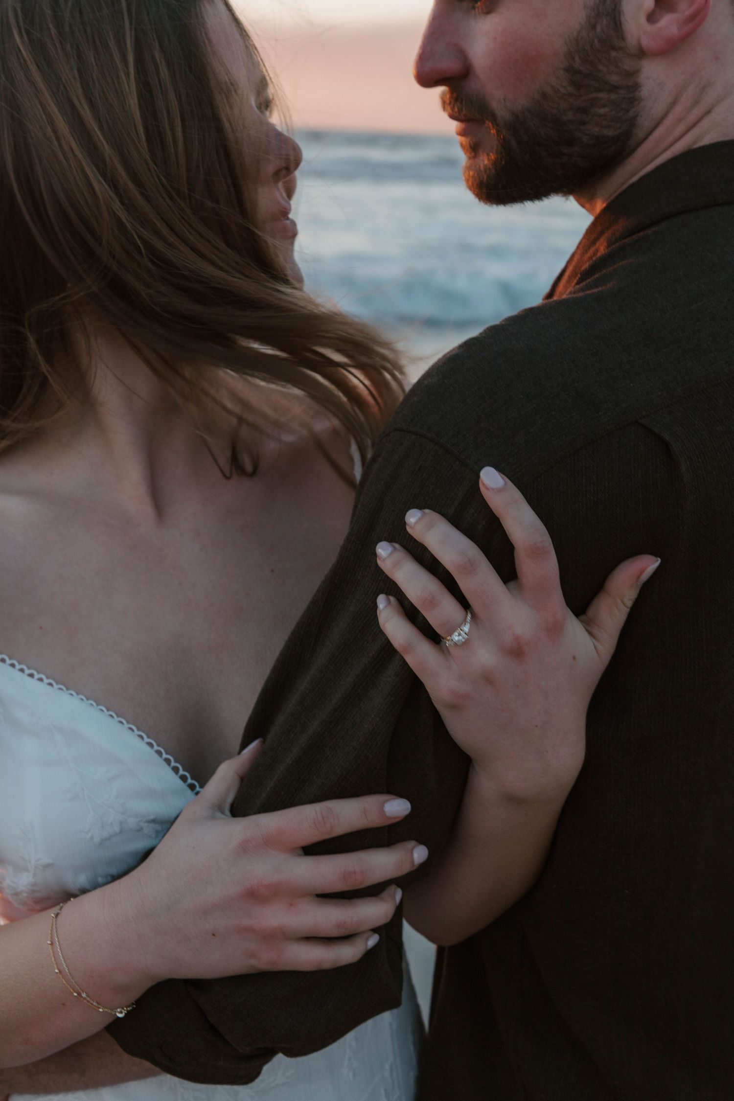 engaged couple hugging at sunset on the beach