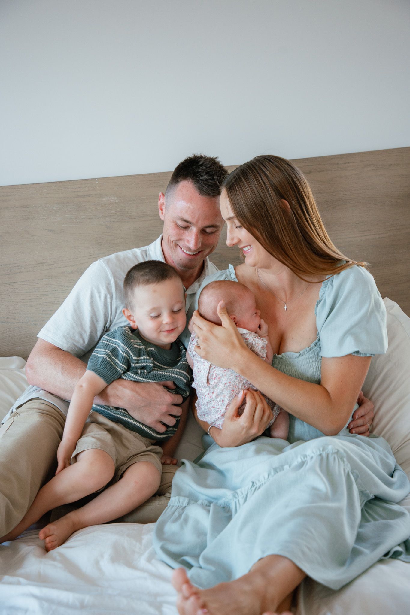 family sitting in bed at home smiling and hugging