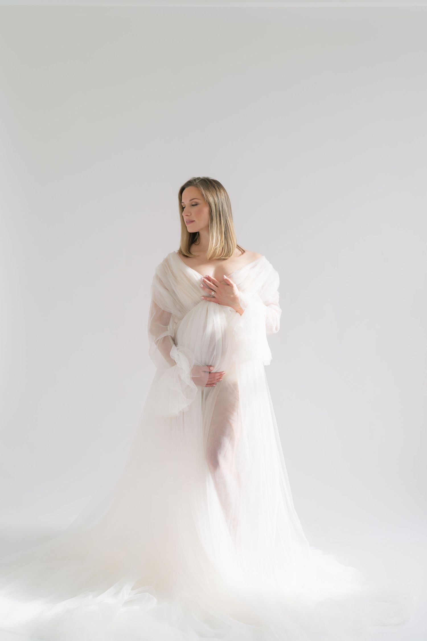 Hands gently resting on baby bump in a natural light maternity studio in Valparaiso, Indiana.
