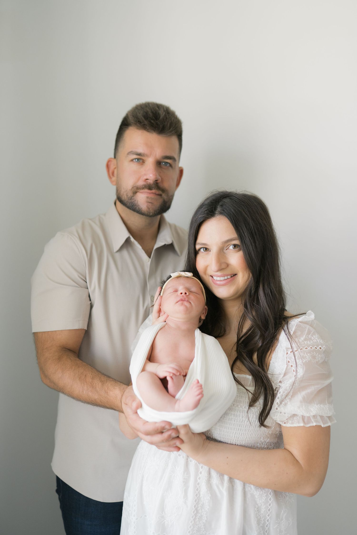 New parents cuddling their newborn in a cozy at-home session in Valparaiso, Indiana.