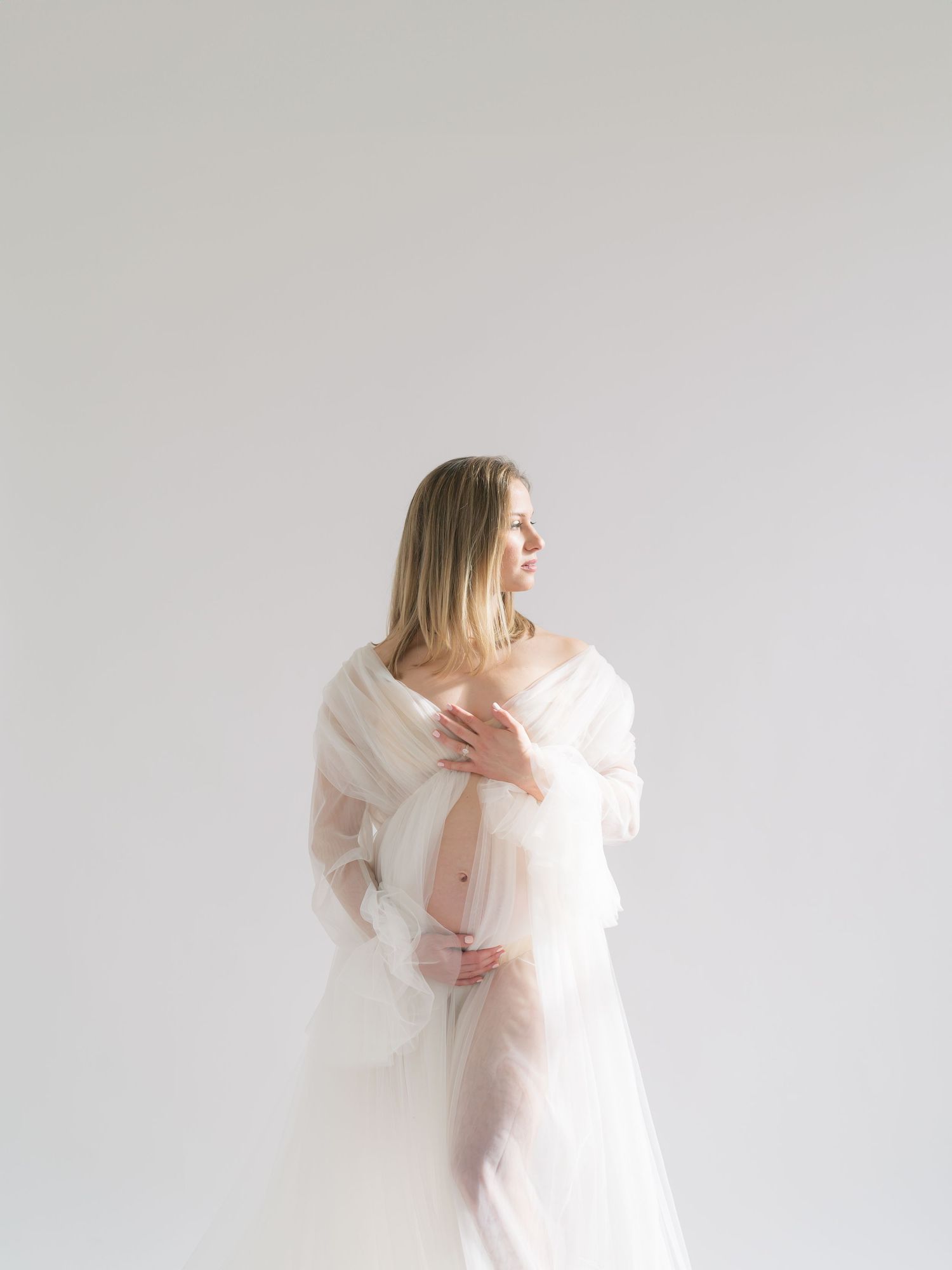 Hands gently resting on baby bump in a natural light maternity studio in Valparaiso, Indiana.