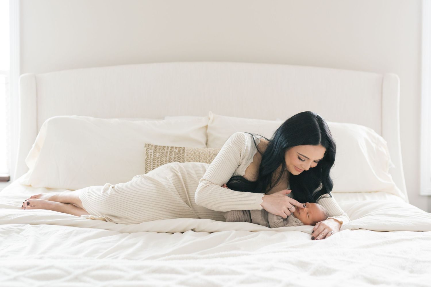 Mother cuddling with her newborn baby in the master bedroom during an in home newborn lifestyle photo session in valparaiso indiana