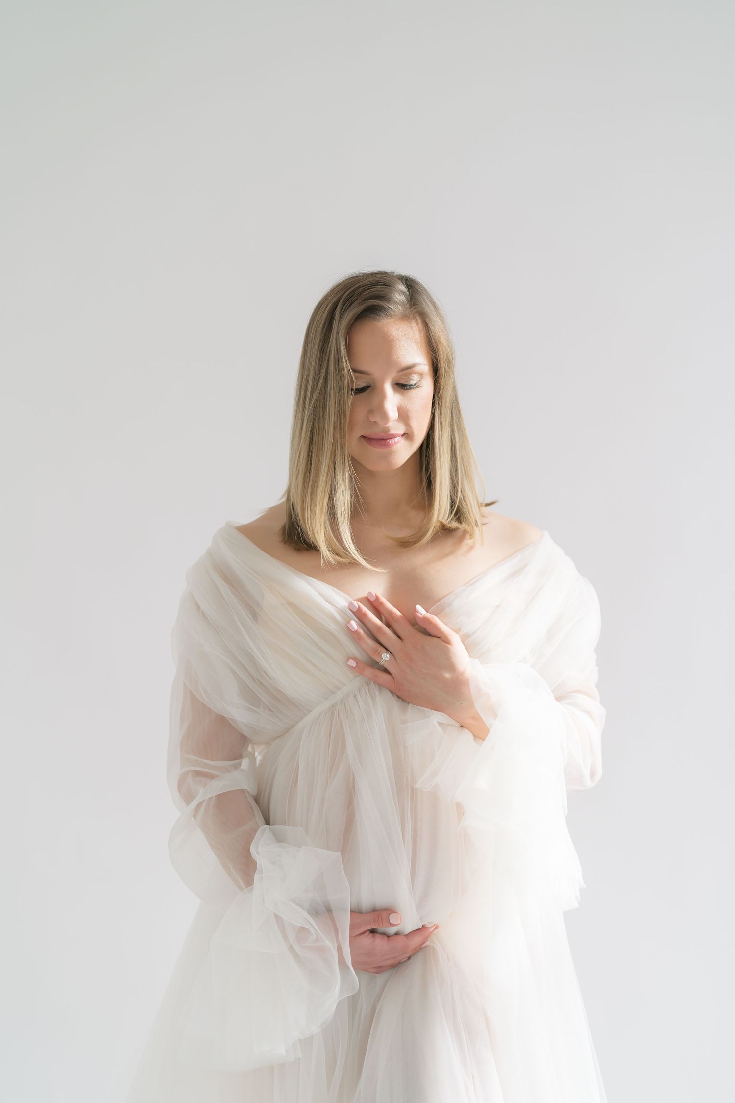 Hands gently resting on baby bump in a natural light maternity studio in Valparaiso, Indiana.