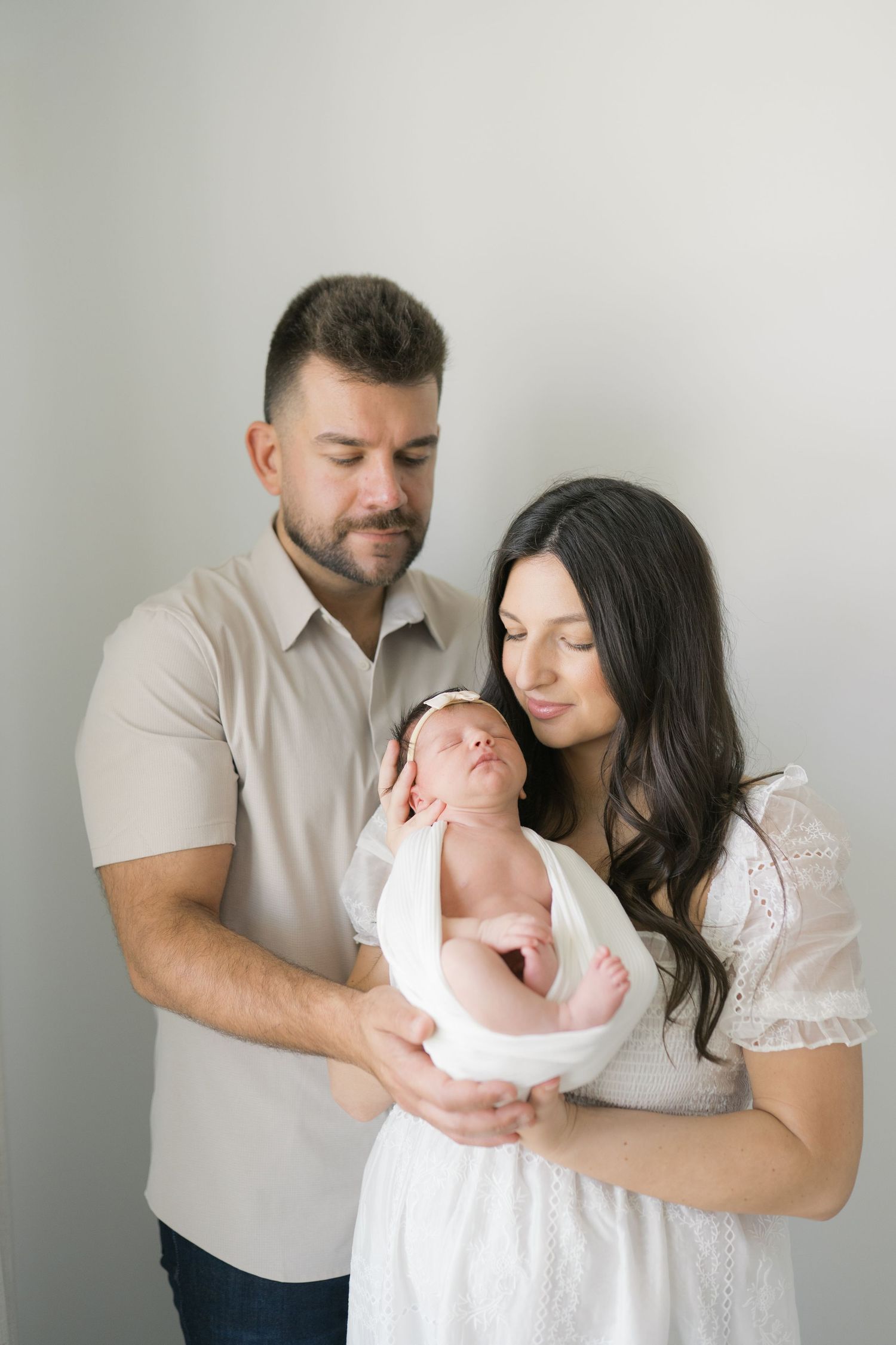 New parents cuddling their newborn in a cozy at-home session in Valparaiso, Indiana.