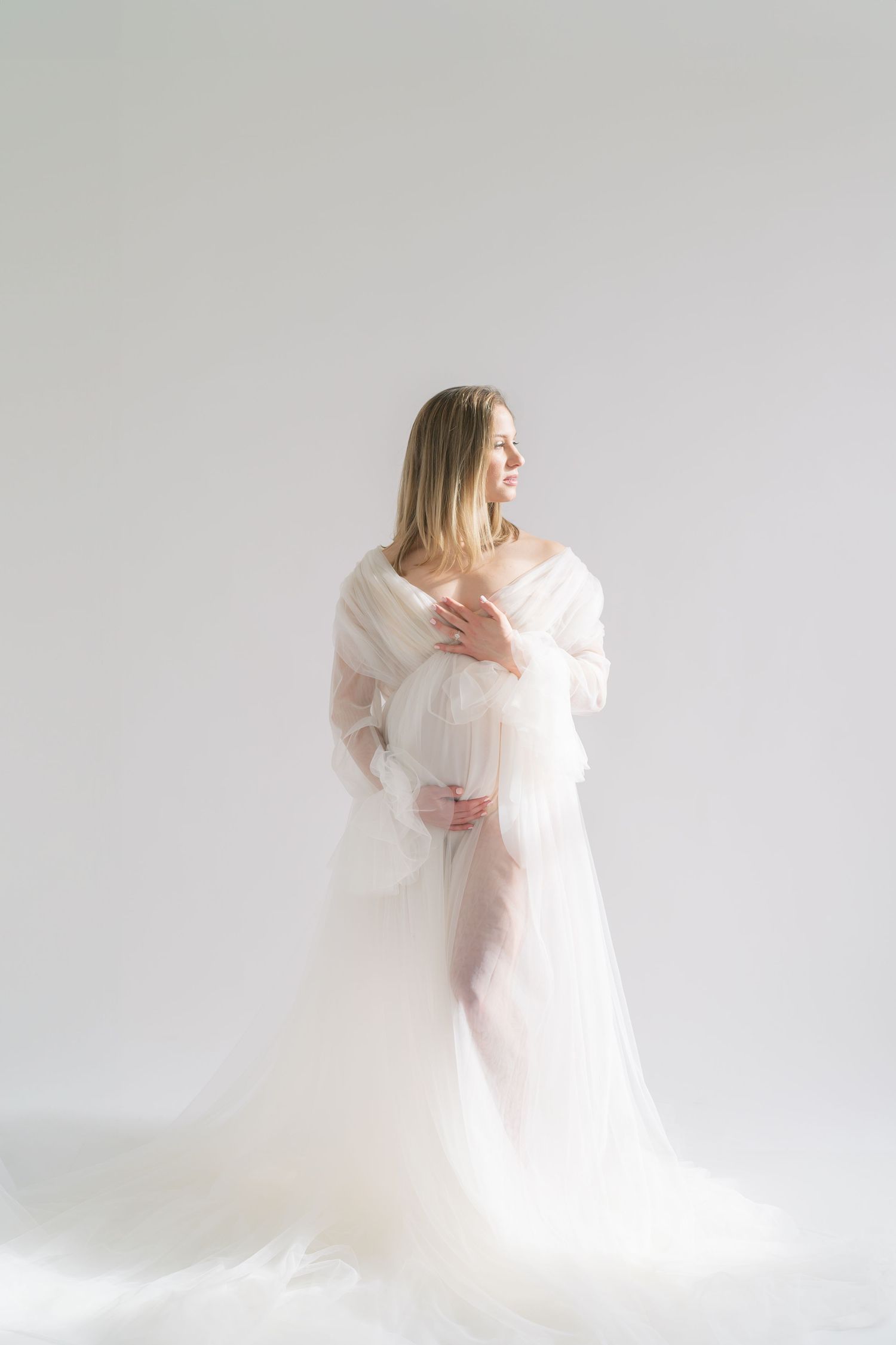 Hands gently resting on baby bump in a natural light maternity studio in Valparaiso, Indiana.