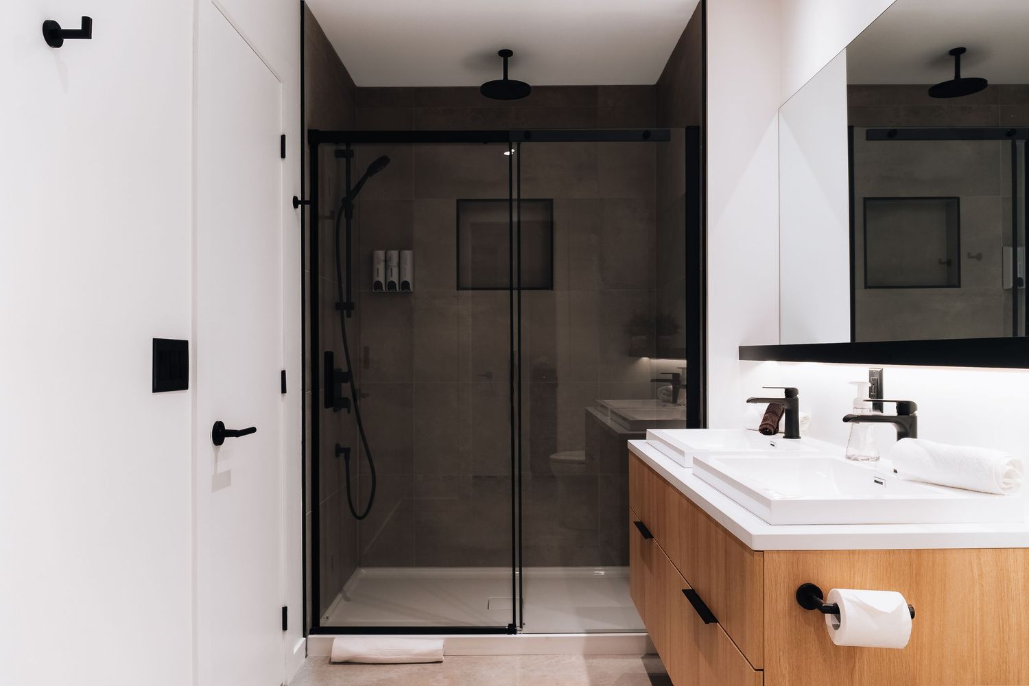 Sleek bathroom interior featuring black framed shower doors and wood paneling with modern fixtures.