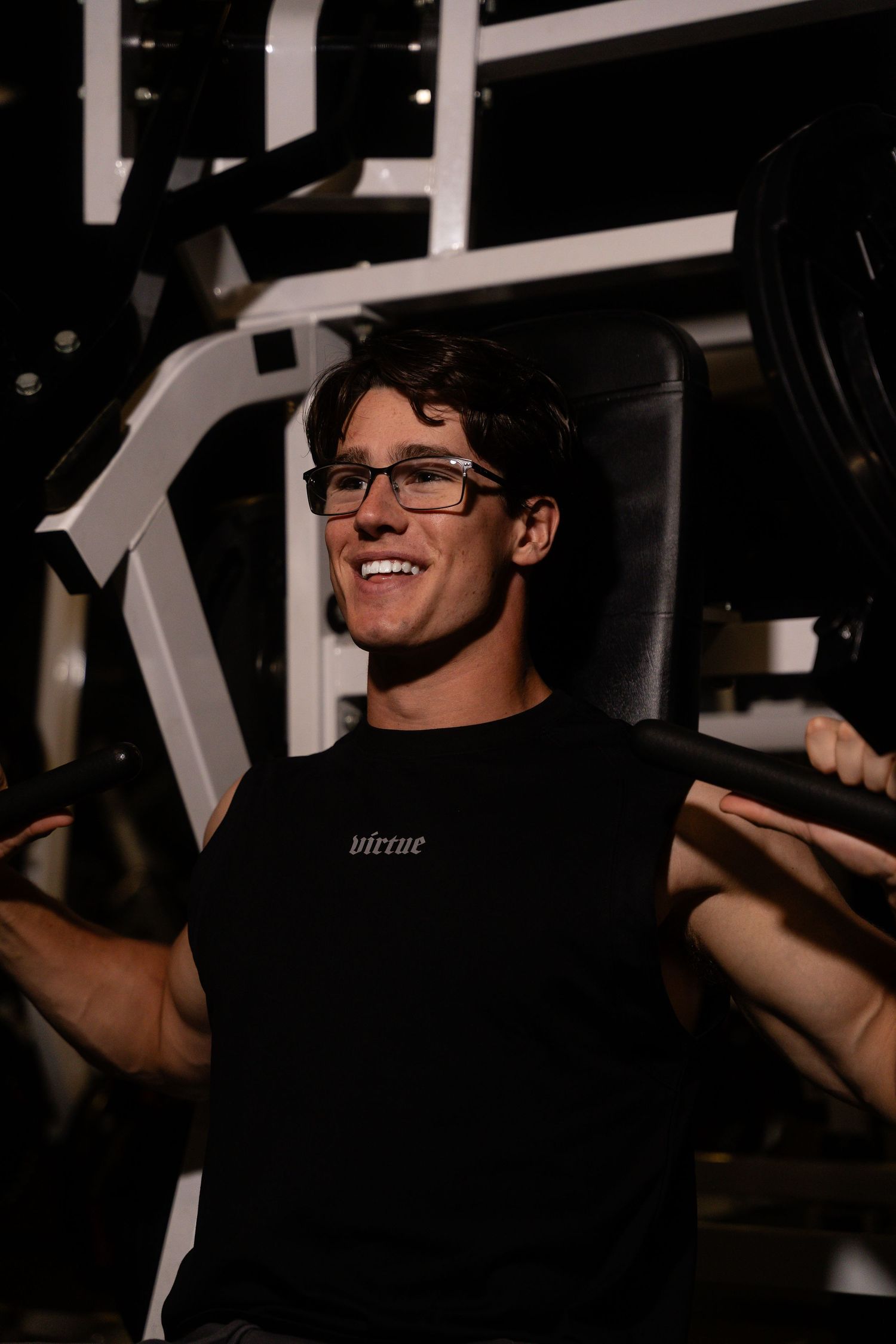 Person smiling while working out in gym wearing black virtue branded clothing.