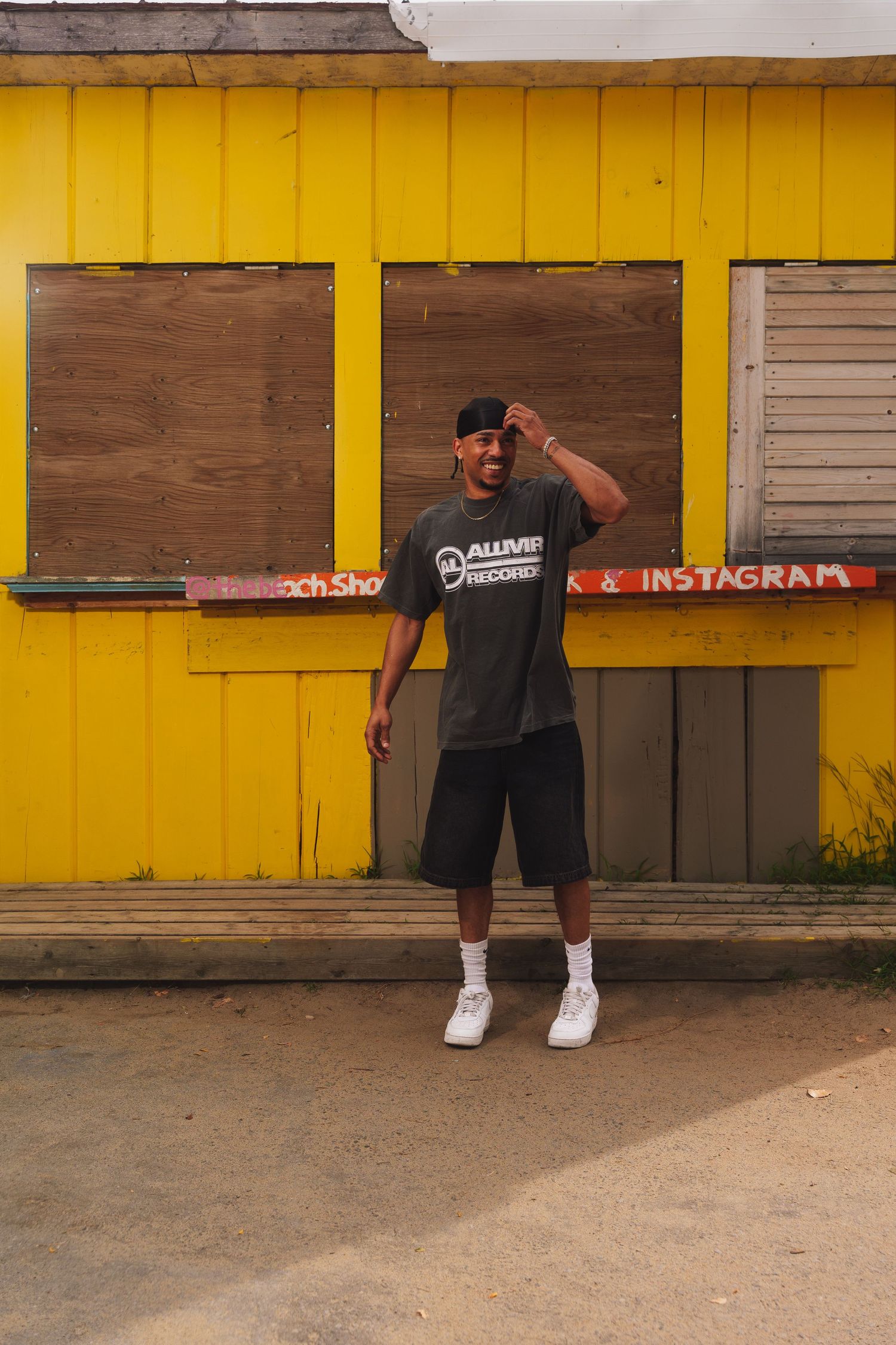 Person posing in front of yellow wall with wooden shutters.