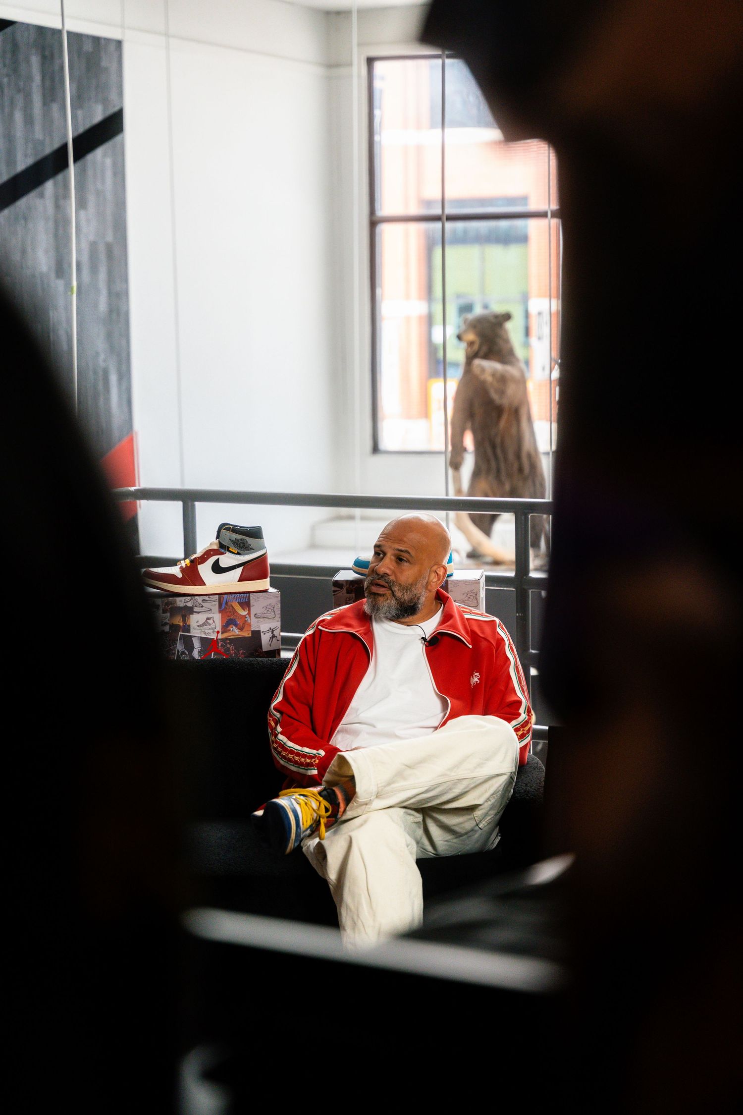 Interior scene through window showing person relaxing in casual athletic wear.