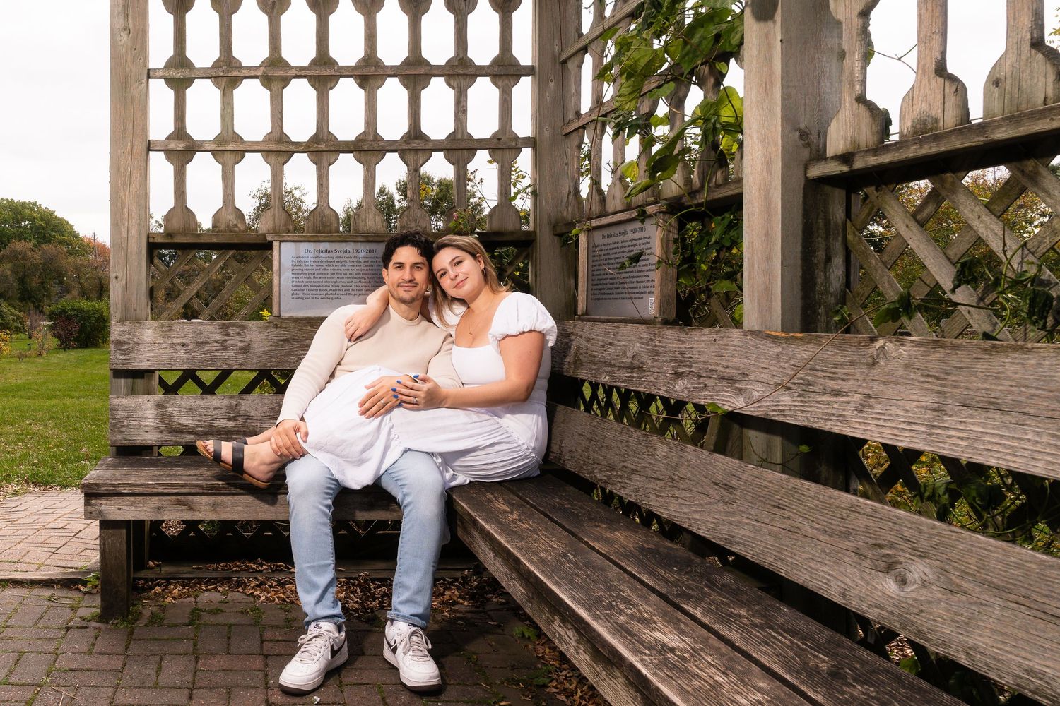 A couple sits together on a wooden porch bench in a romantic outdoor setting.
