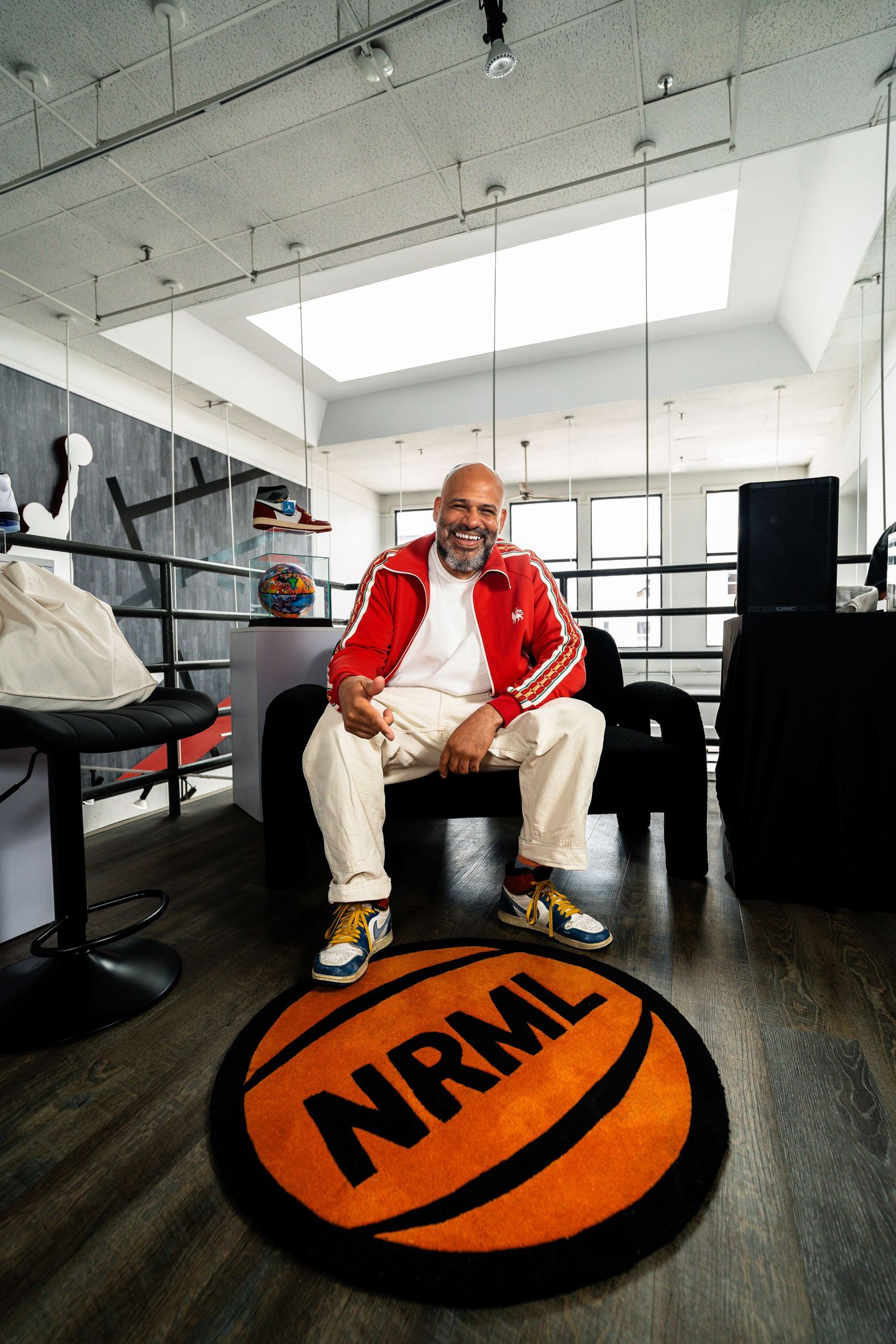 A series of photos showing someone sitting on a large orange circular logo mat in an office space.