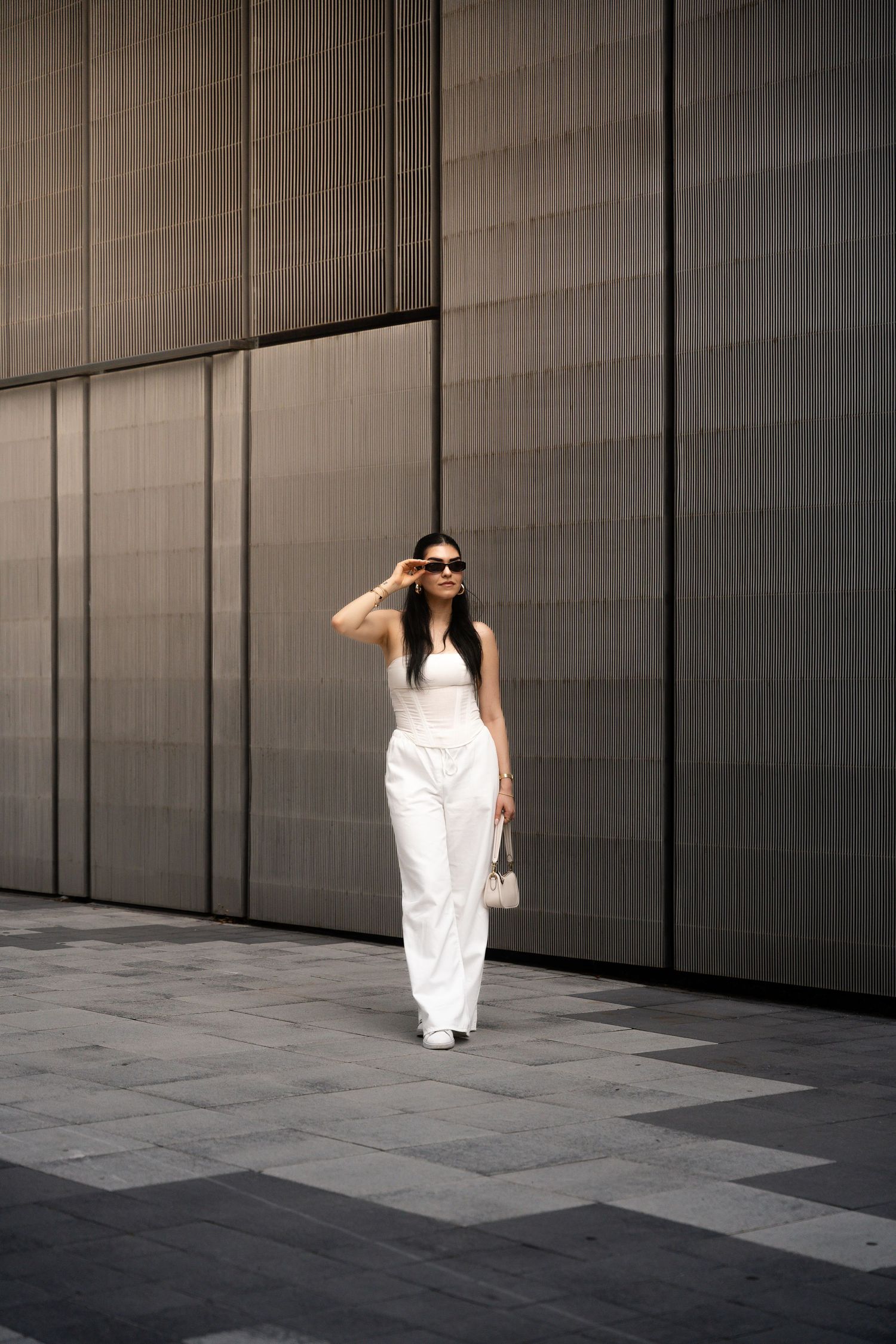 Figure in white clothing walks through minimalist architectural space with dark walls.