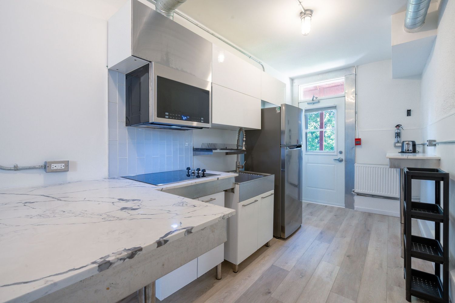 Modern white kitchen with stainless steel appliances and clean lines in an open concept layout.