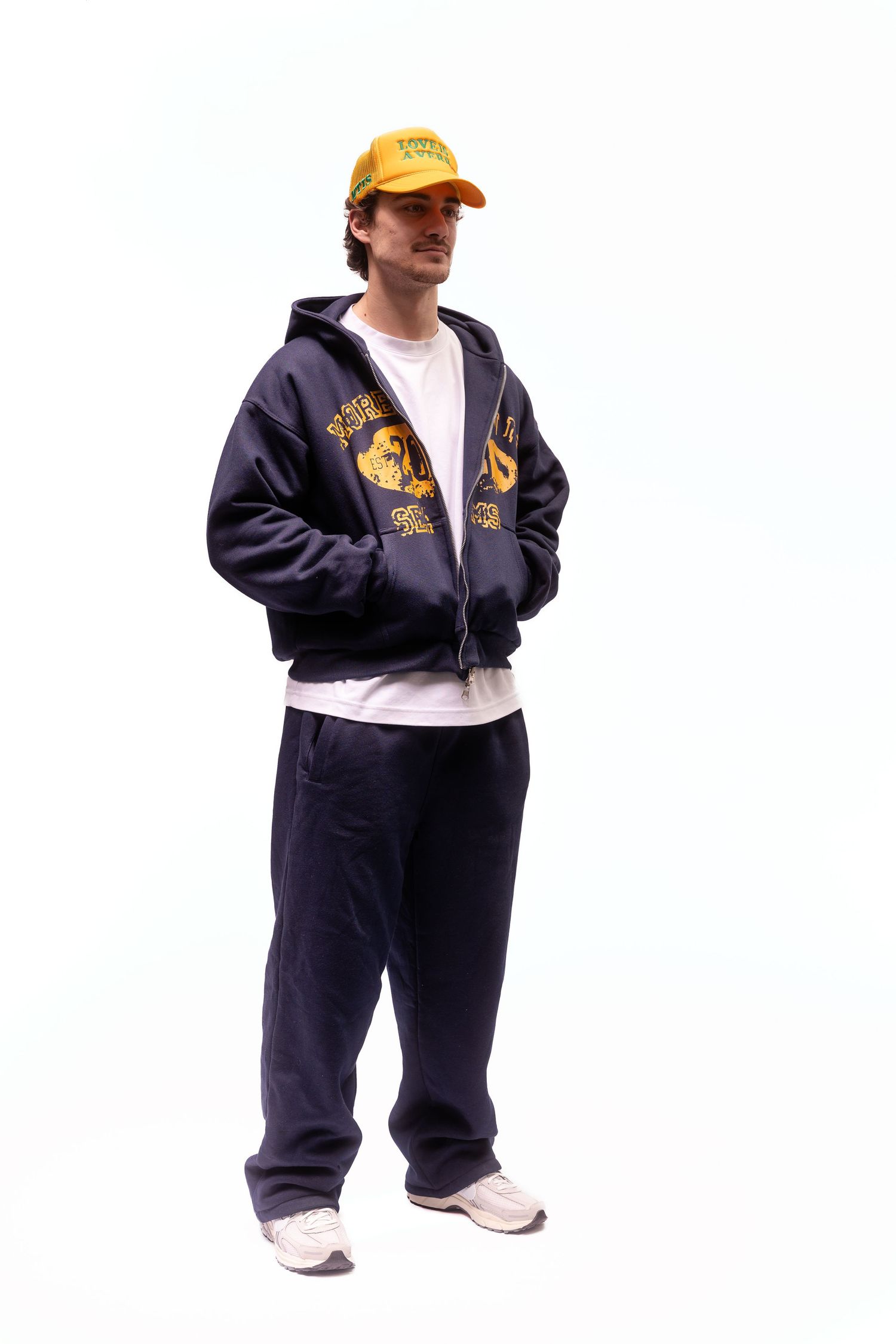 Person wearing navy tracksuit and yellow cap shown in multiple standing positions.