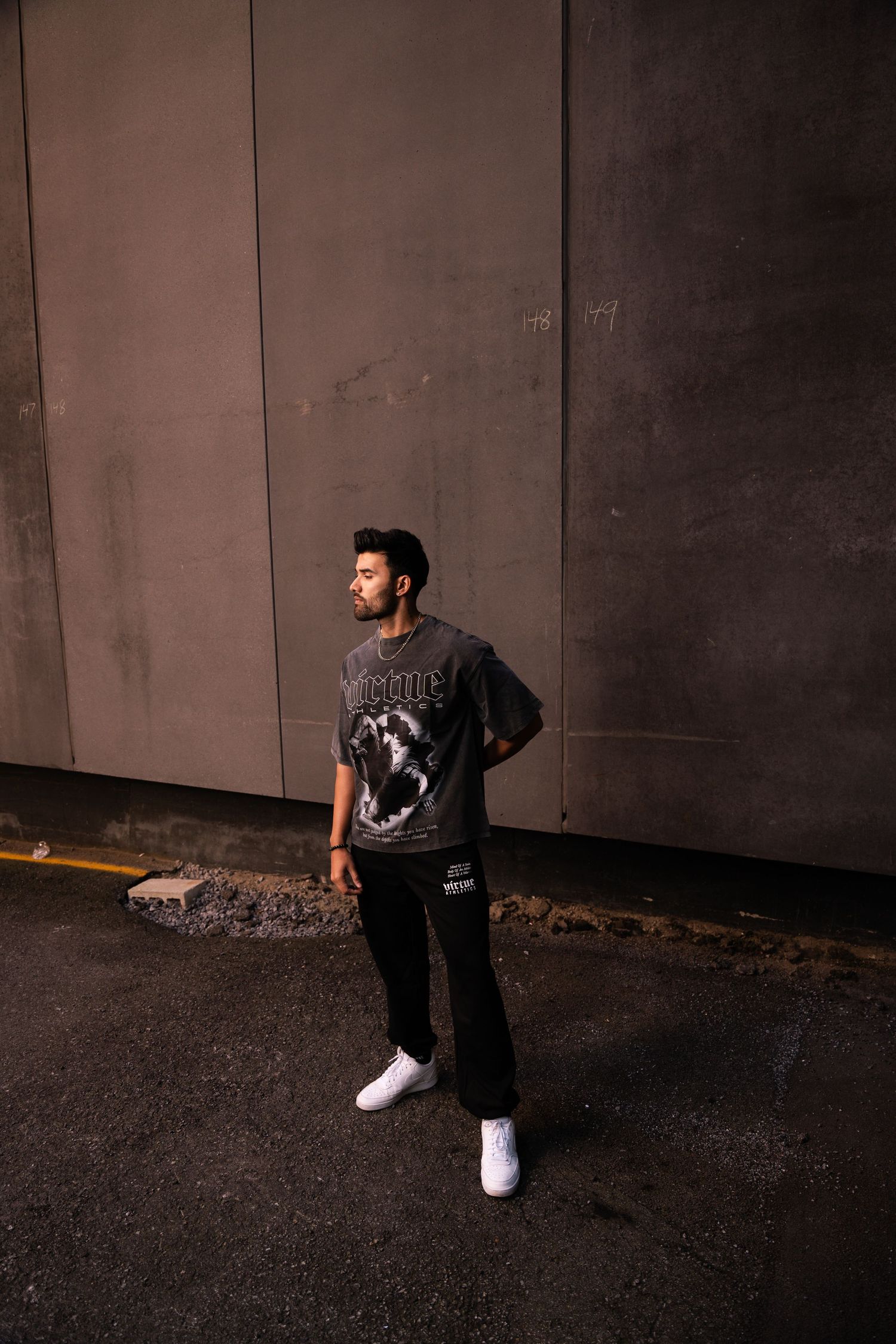 Urban fashion photo shoot against industrial concrete wall backdrop.