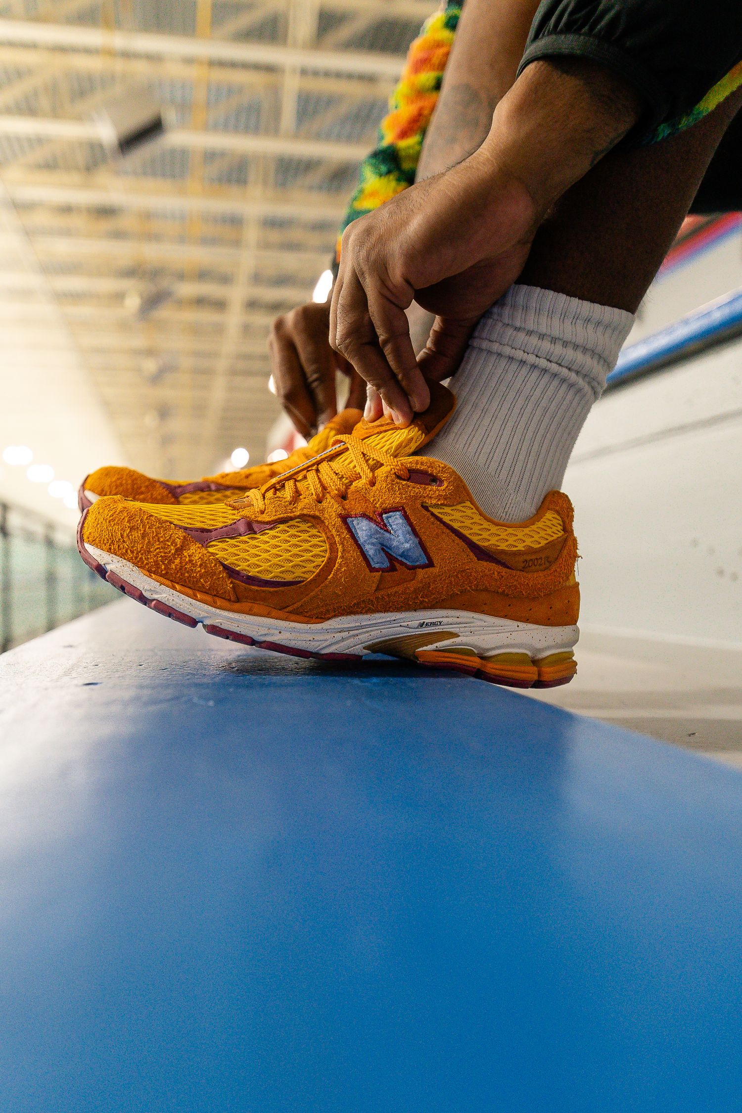 Close-up of bright orange athletic shoes being laced up on blue surface.