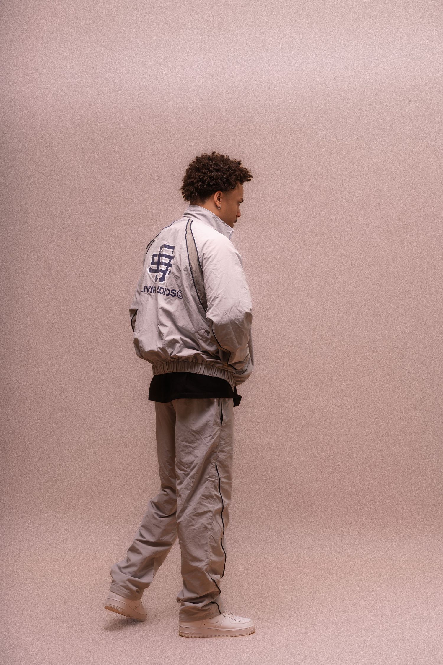 Several people in white tracksuits shown from behind against a pink backdrop.