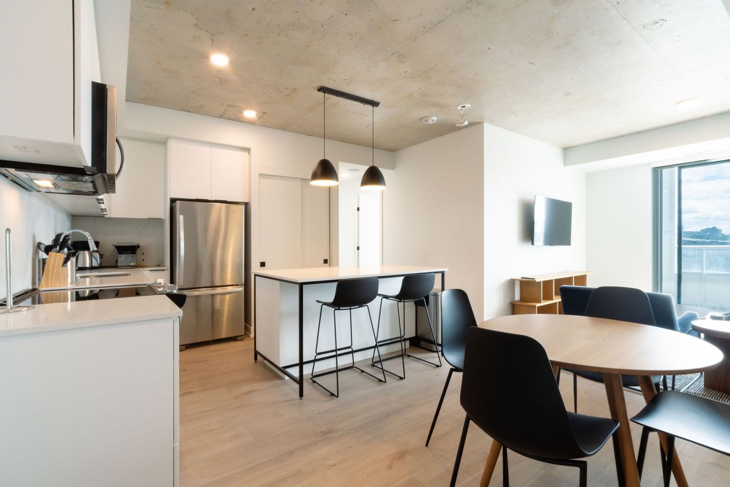 Open concept living and dining area with industrial ceiling and modern furniture.