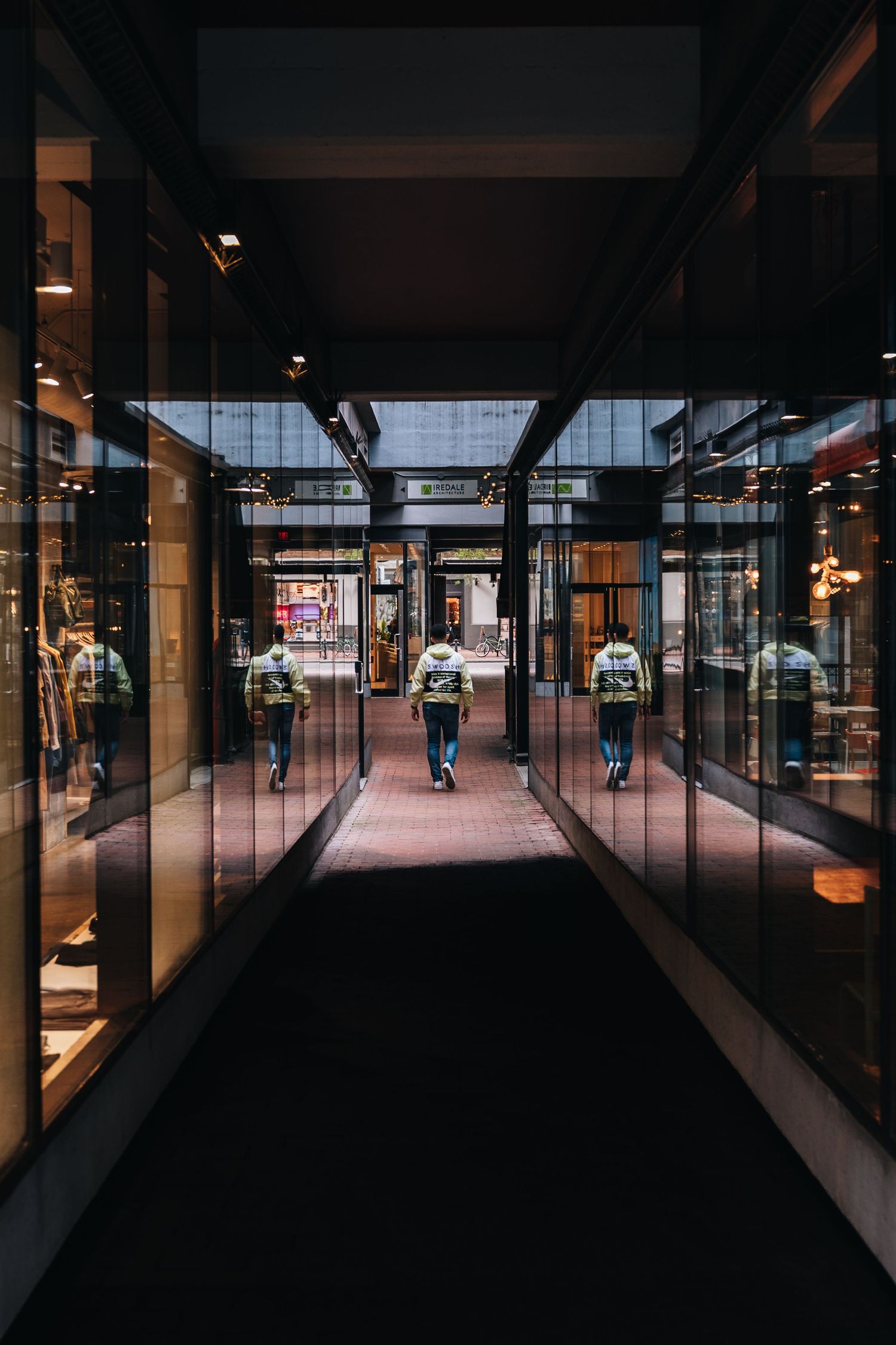 Modern shopping mall interior with glass walls and columns creating dramatic perspective.